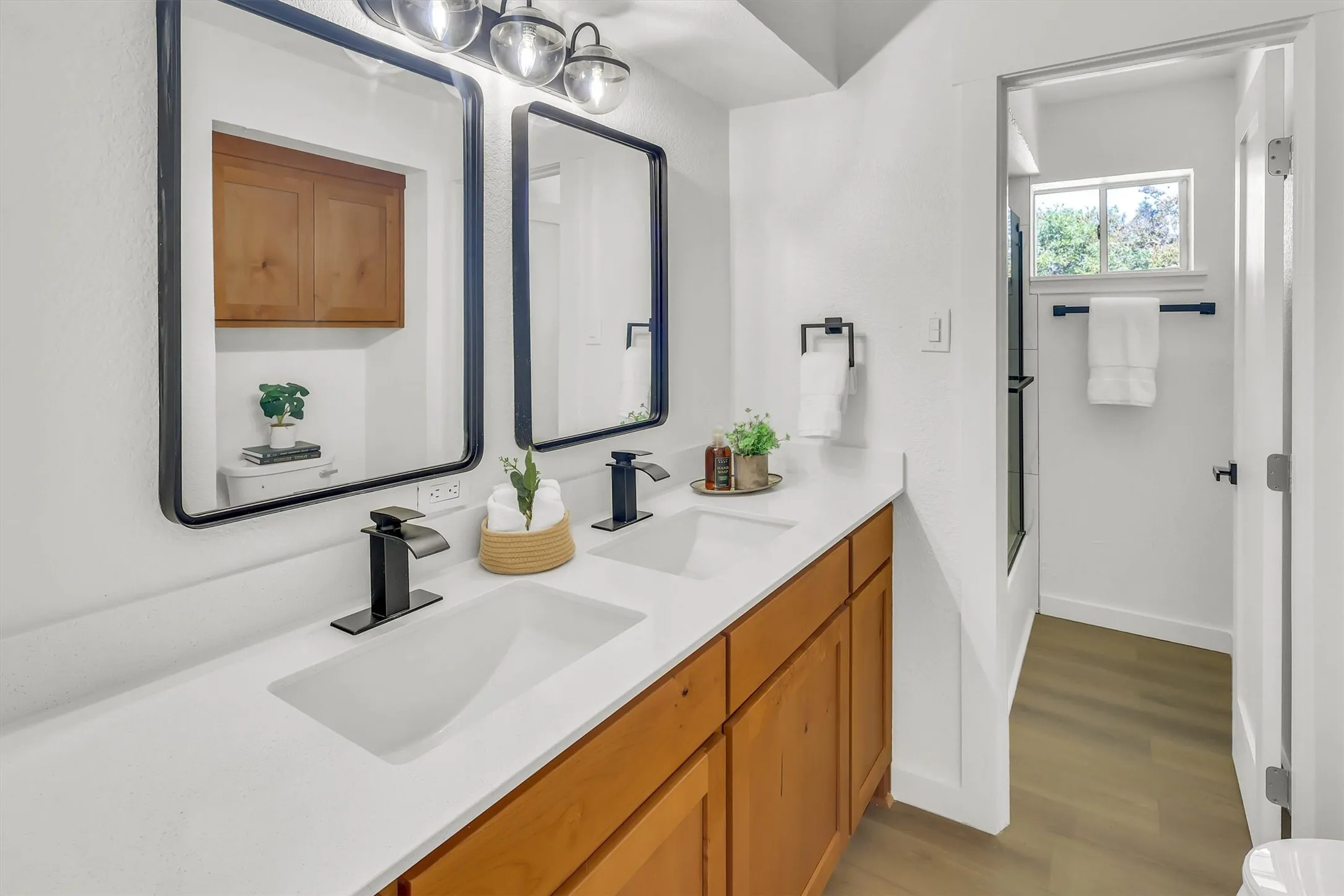 Double vanity with integrated rectangular sinks, white countertop, and wood-finish cabinetry