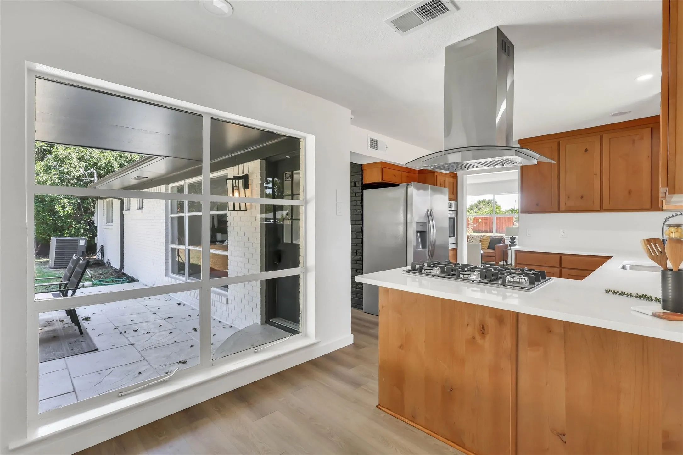 Kitchen featuring wood cabinetry, white countertops, built-in gas range, stainless steel range hood, and wood-finish flooring