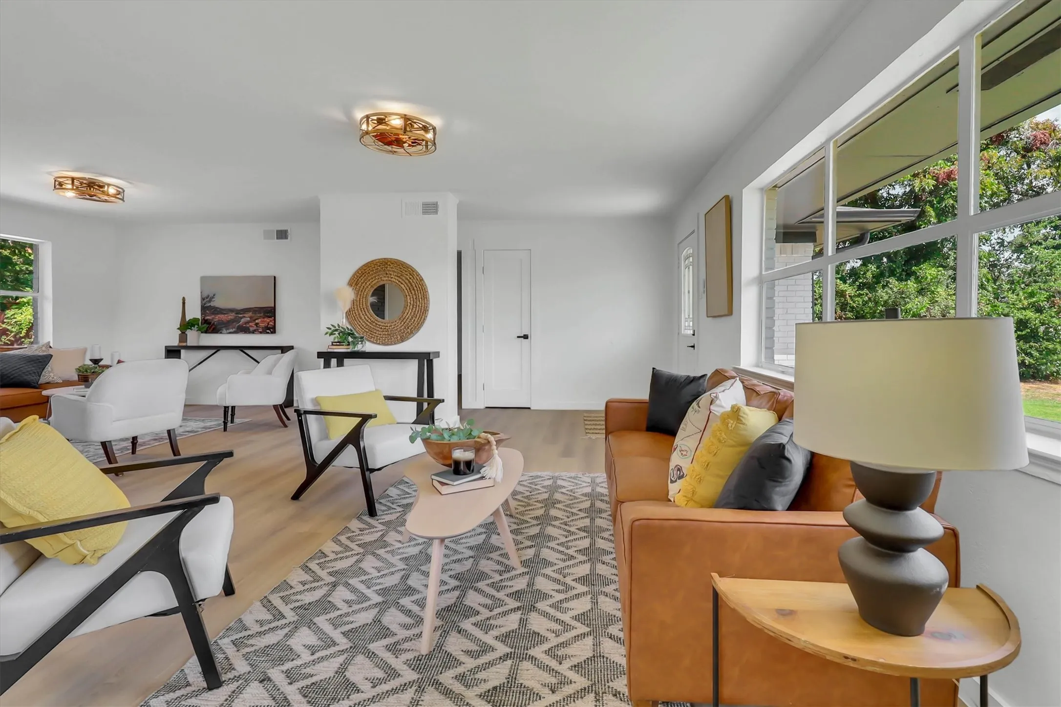 Expansive living area with large multi-pane windows, wood-finish flooring, recessed lighting, and modern ceiling fixtures