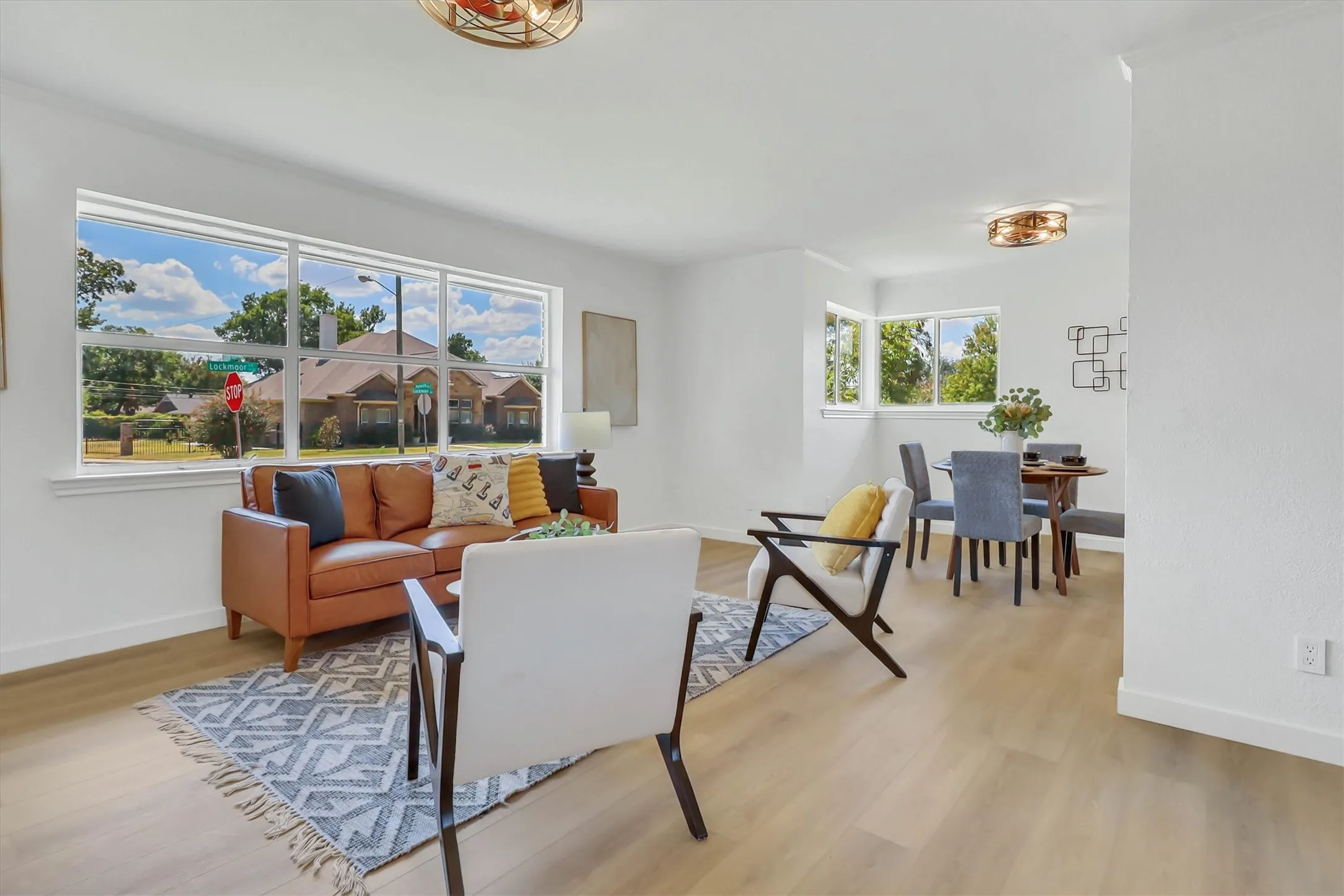 Bright open-concept living space with expansive windows, light wood-finish flooring, and recessed ceiling lighting