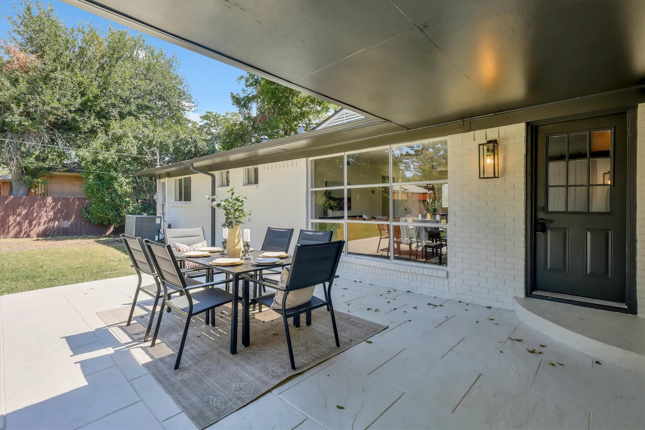 Covered patio featuring large format pavers, exterior brick, and a black exterior door with glass panels