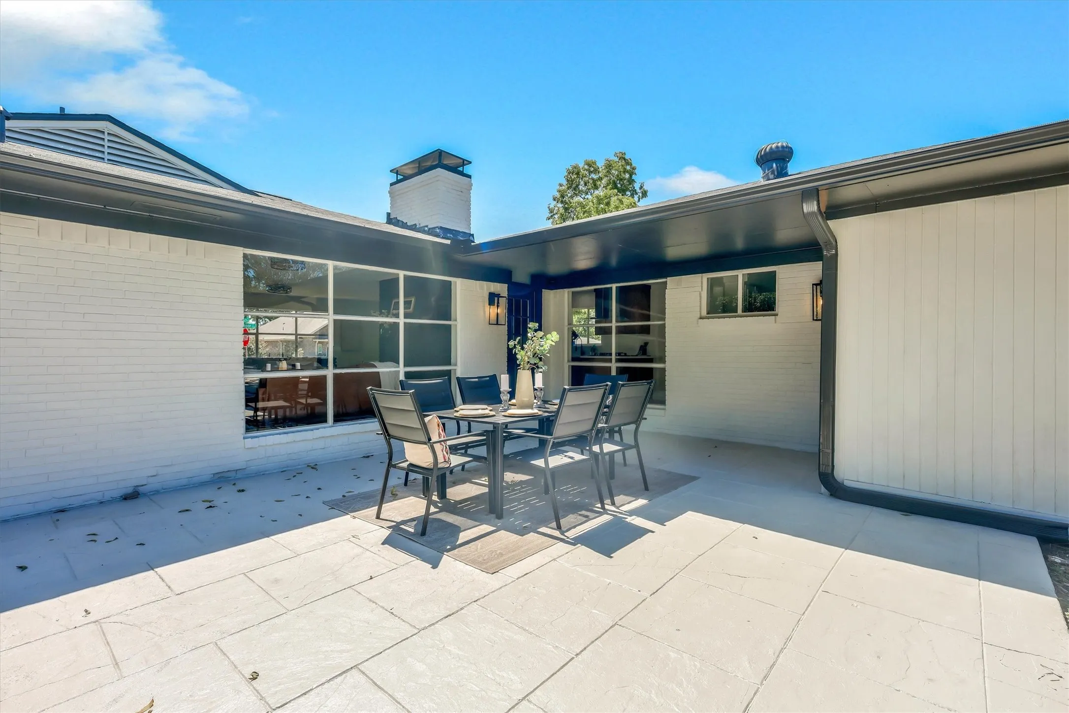 Expansive patio with large format pavers and white brick exterior