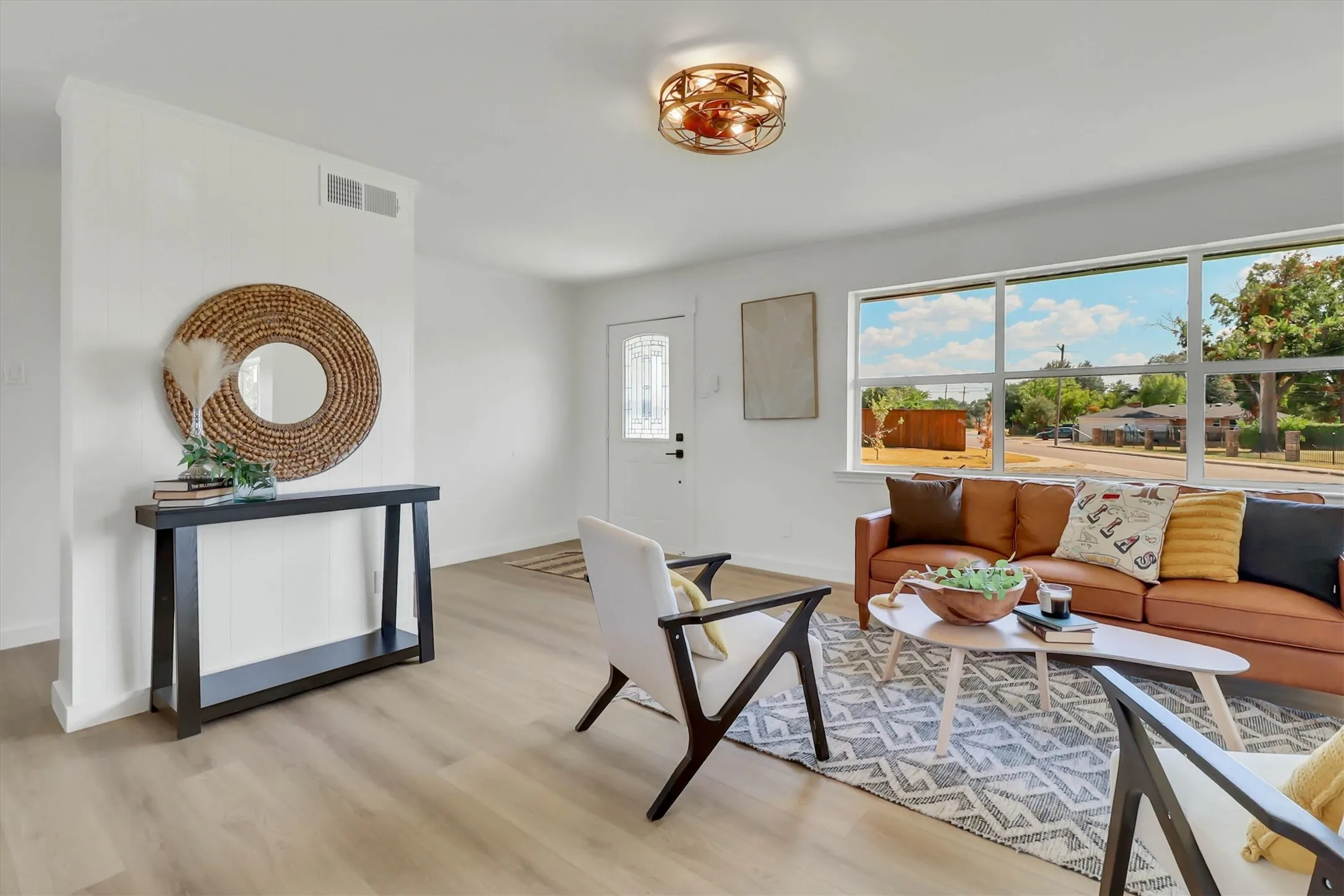 Wood-finish flooring, white walls, and a multi-pane window illuminate this living area