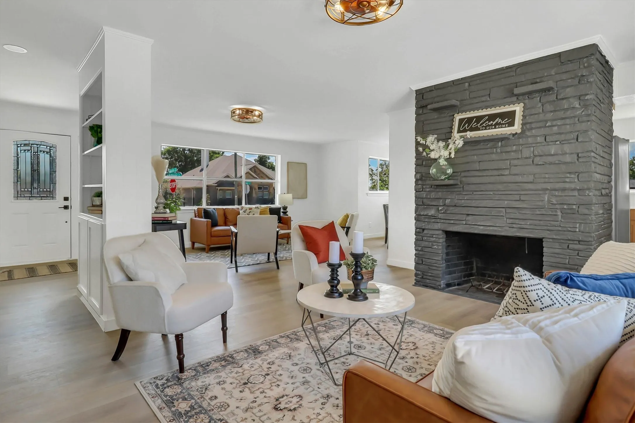 Spacious living area featuring a stone-clad fireplace, wood-finish flooring, built-in shelving, and recessed lighting