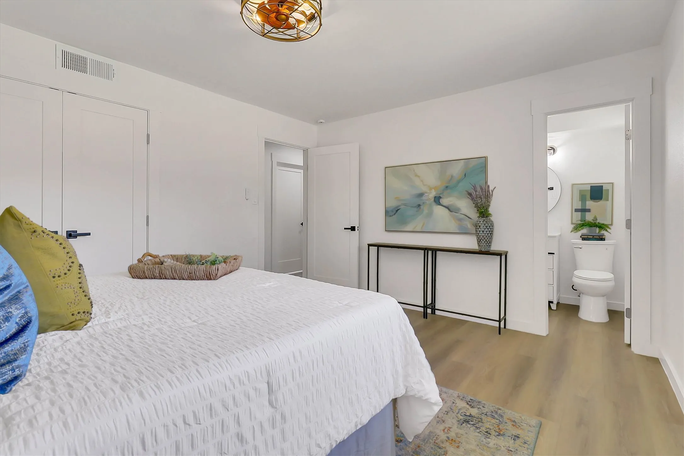 Light wood-finish flooring with white walls and a contemporary ceiling light fixture