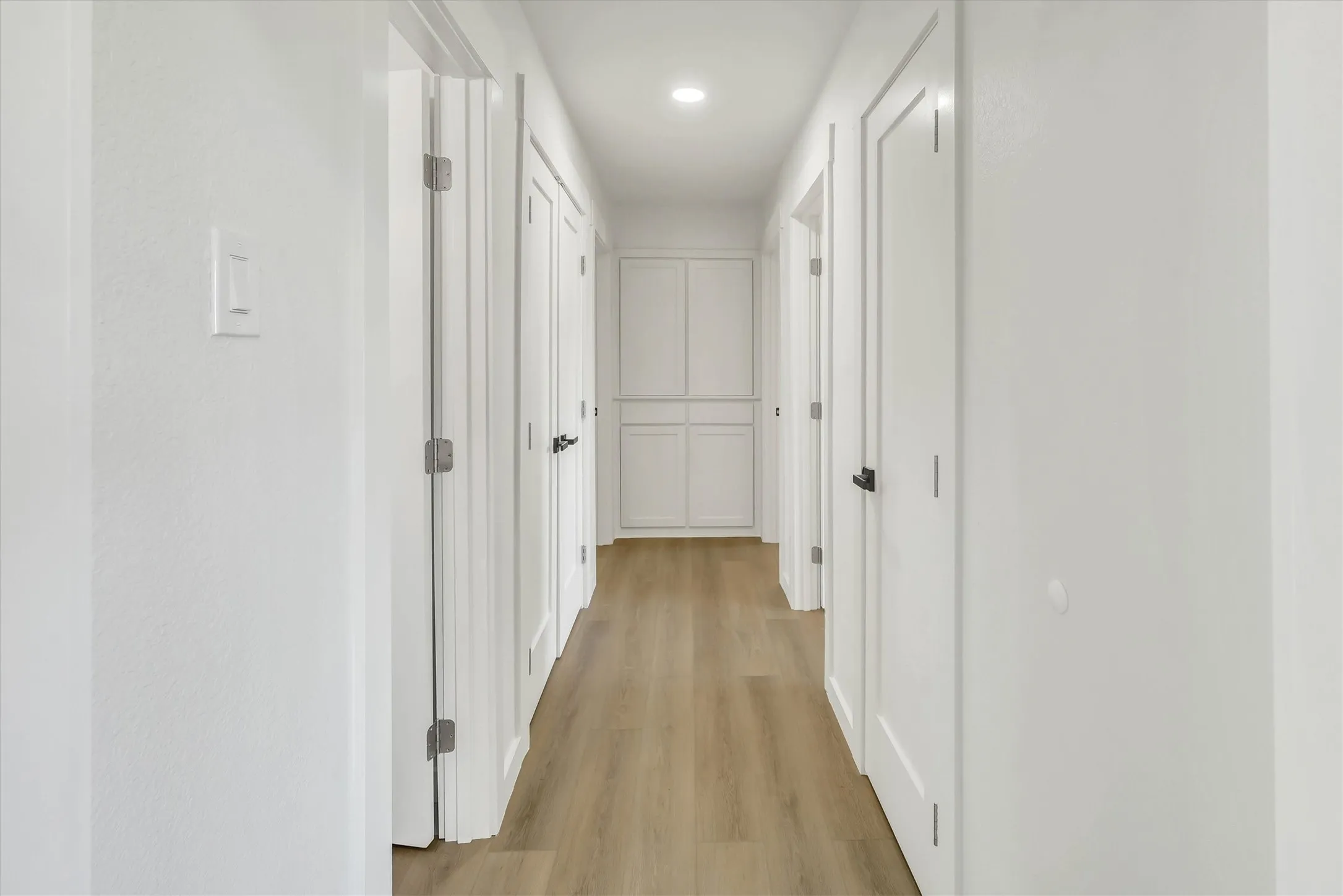 Hallway with wood-finish flooring, recessed lighting, and built-in cabinetry
