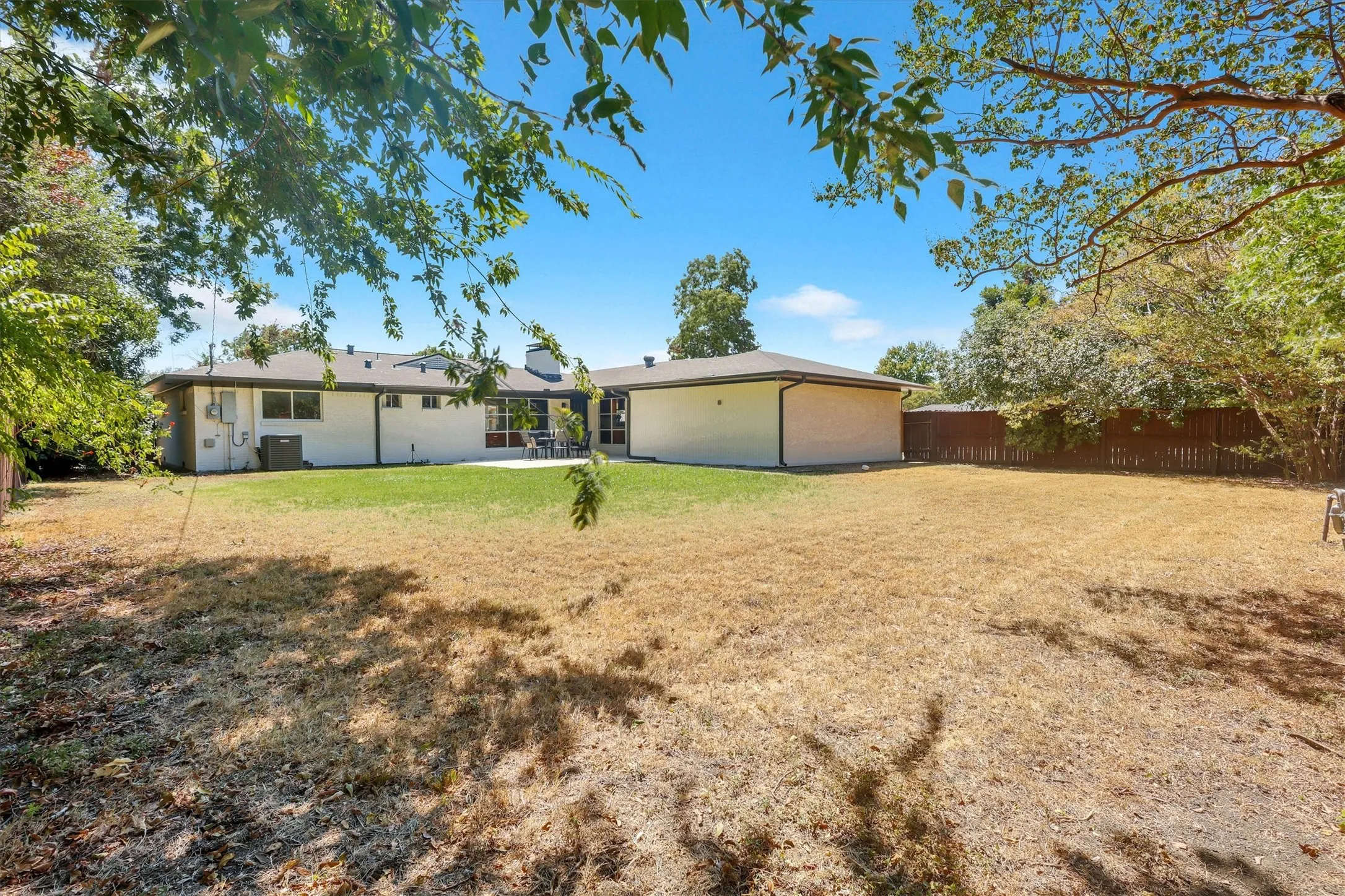 Expansive property featuring a large backyard area, a manicured lawn section, and a concrete patio