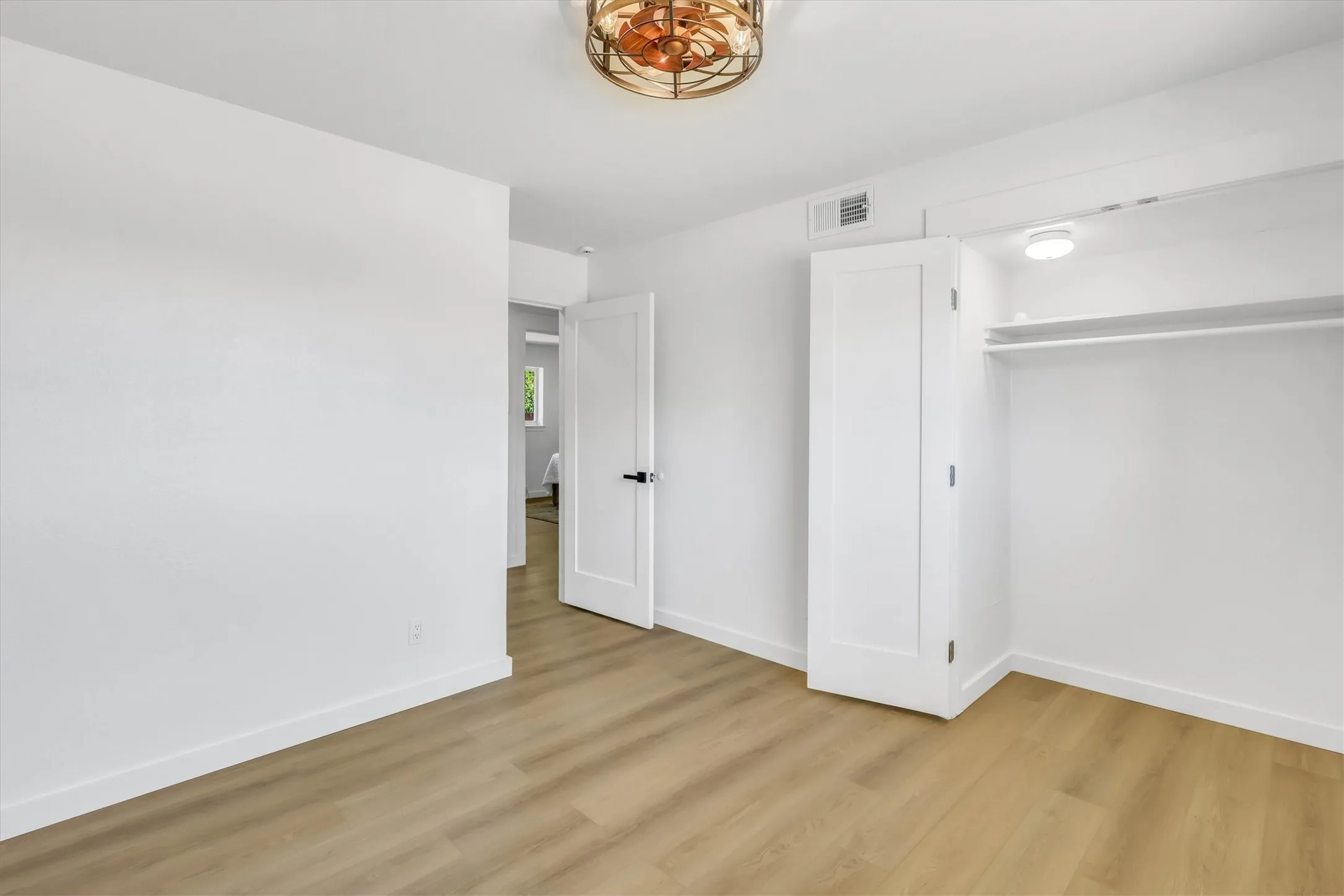 Wood-finish flooring, white walls, and a contemporary ceiling fan