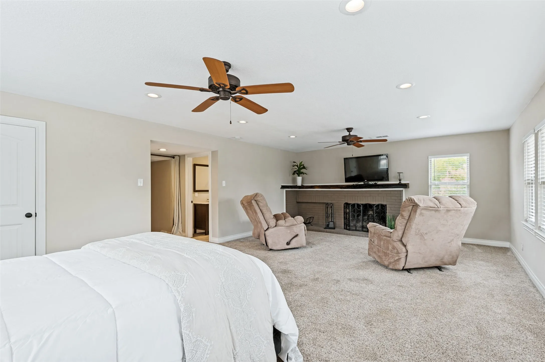 Carpeted room featuring a painted brick fireplace with a dark wood mantel, multiple ceiling fans, recessed lighting, and a white paneled door
