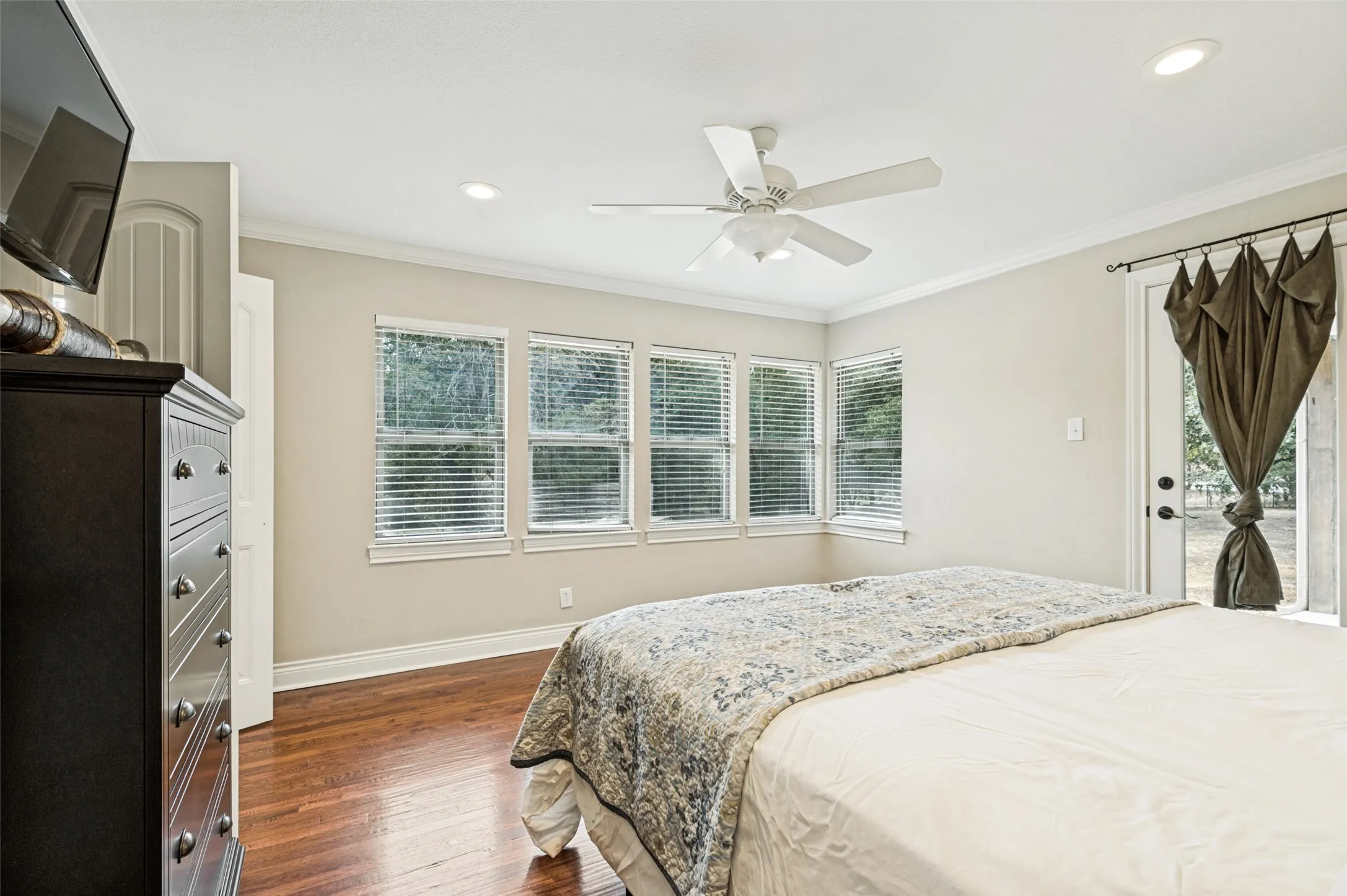 Hardwood flooring, recessed lighting, ceiling fan, multiple windows with blinds, and exterior door access