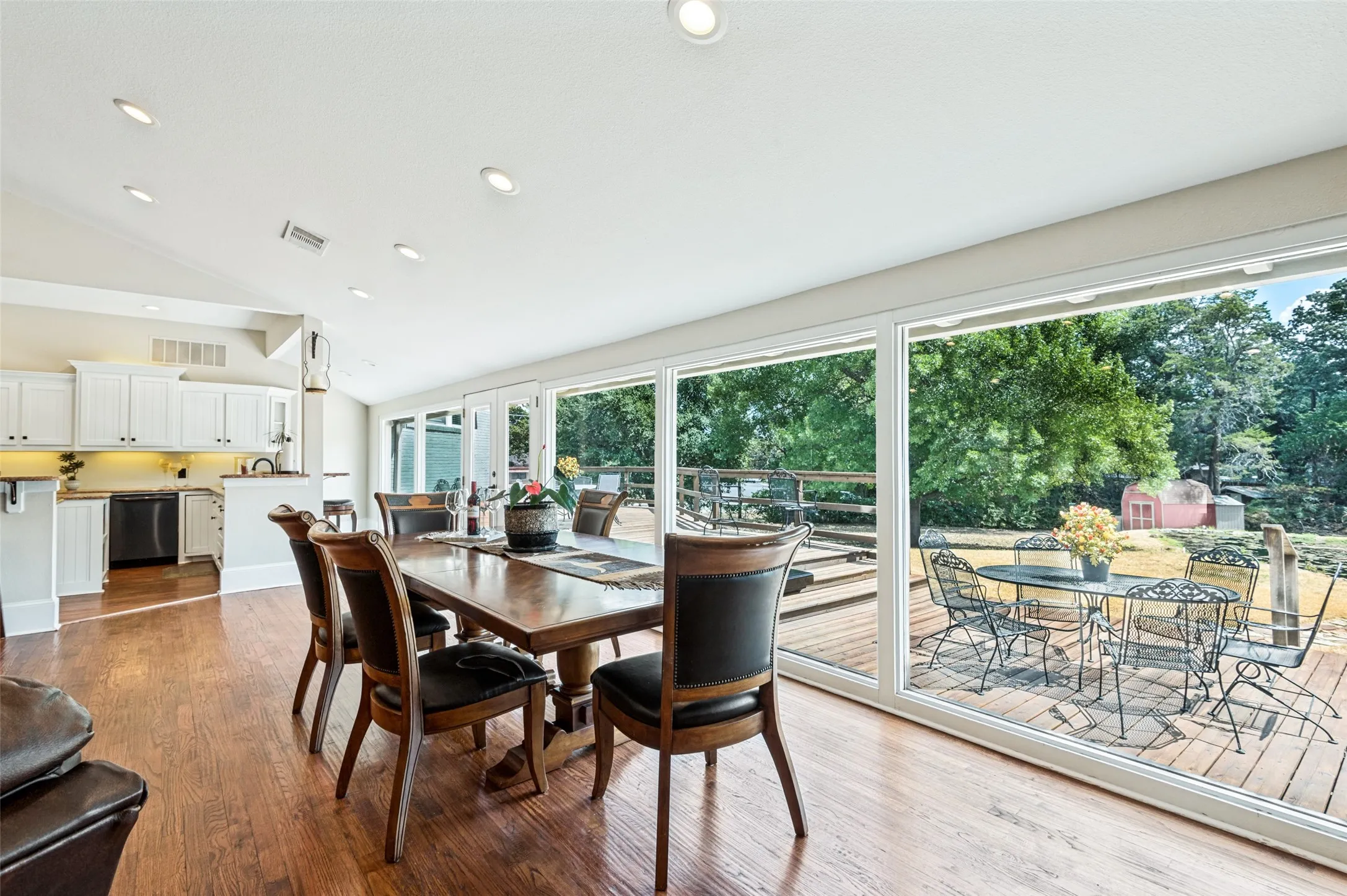 Open-concept living space with wood-finish flooring, recessed lighting, and a vaulted ceiling