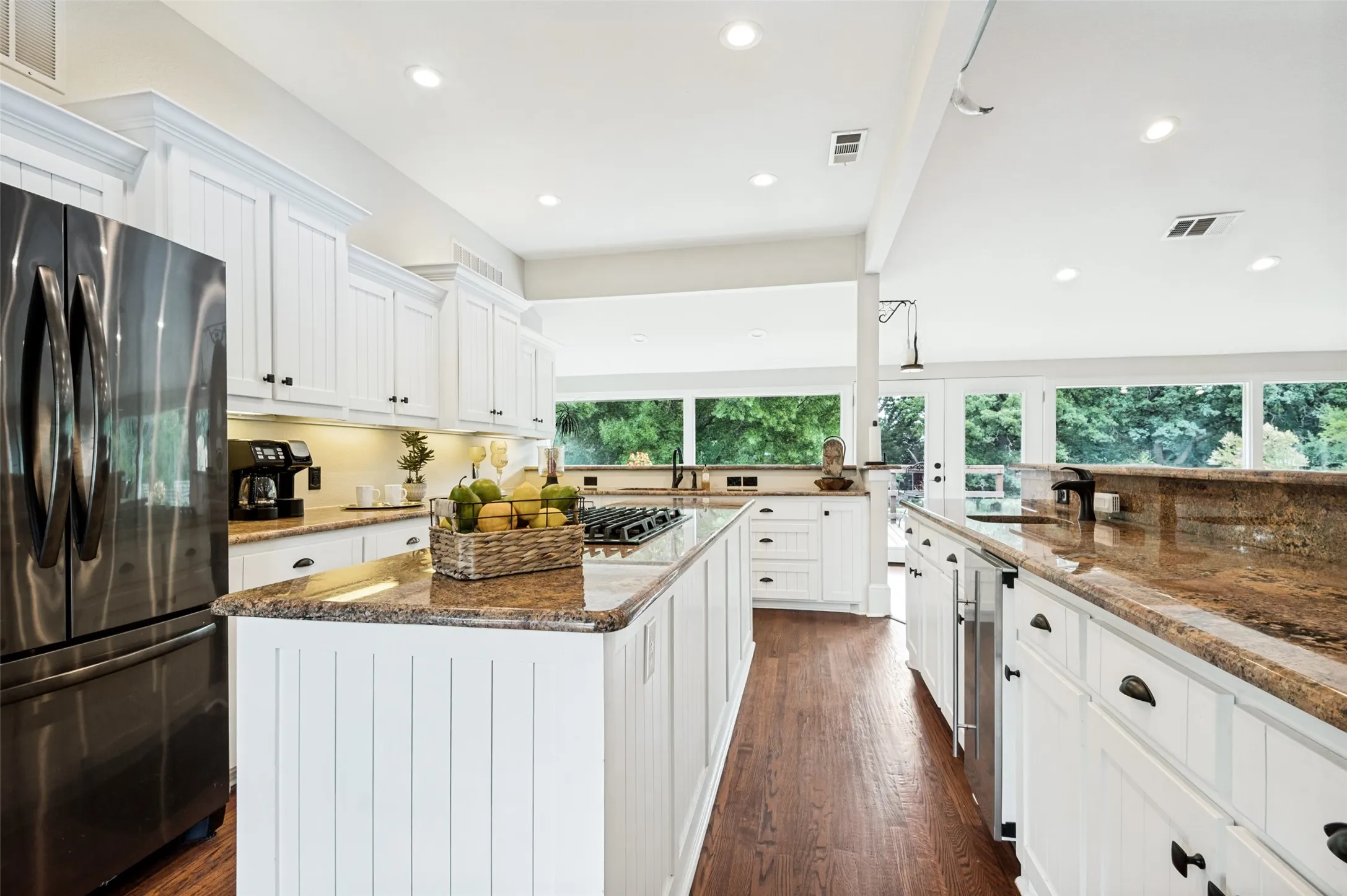 Bright kitchen featuring wood-finish flooring, white cabinetry, recessed lighting, and expansive windows