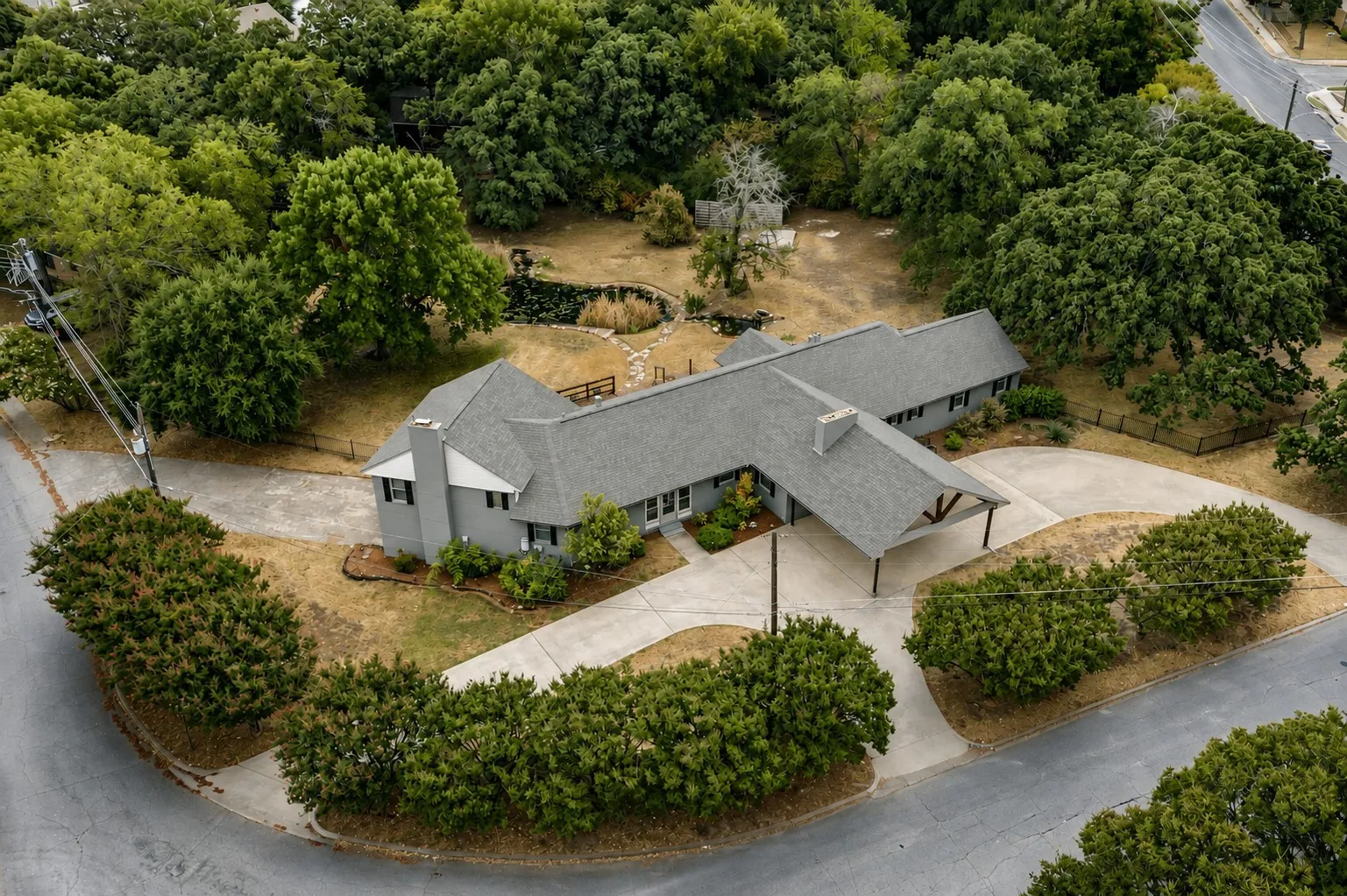 Expansive property with mature trees, a private pond, and a concrete driveway
