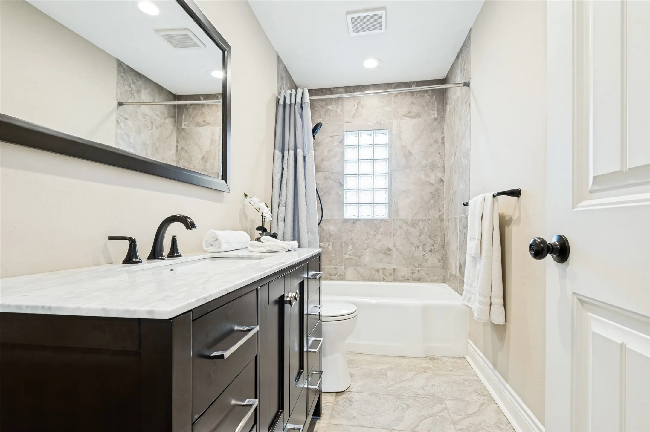 2nd primary bathroom with integrated vanity with a stone countertop, dark wood-finish cabinetry, and black fixtures