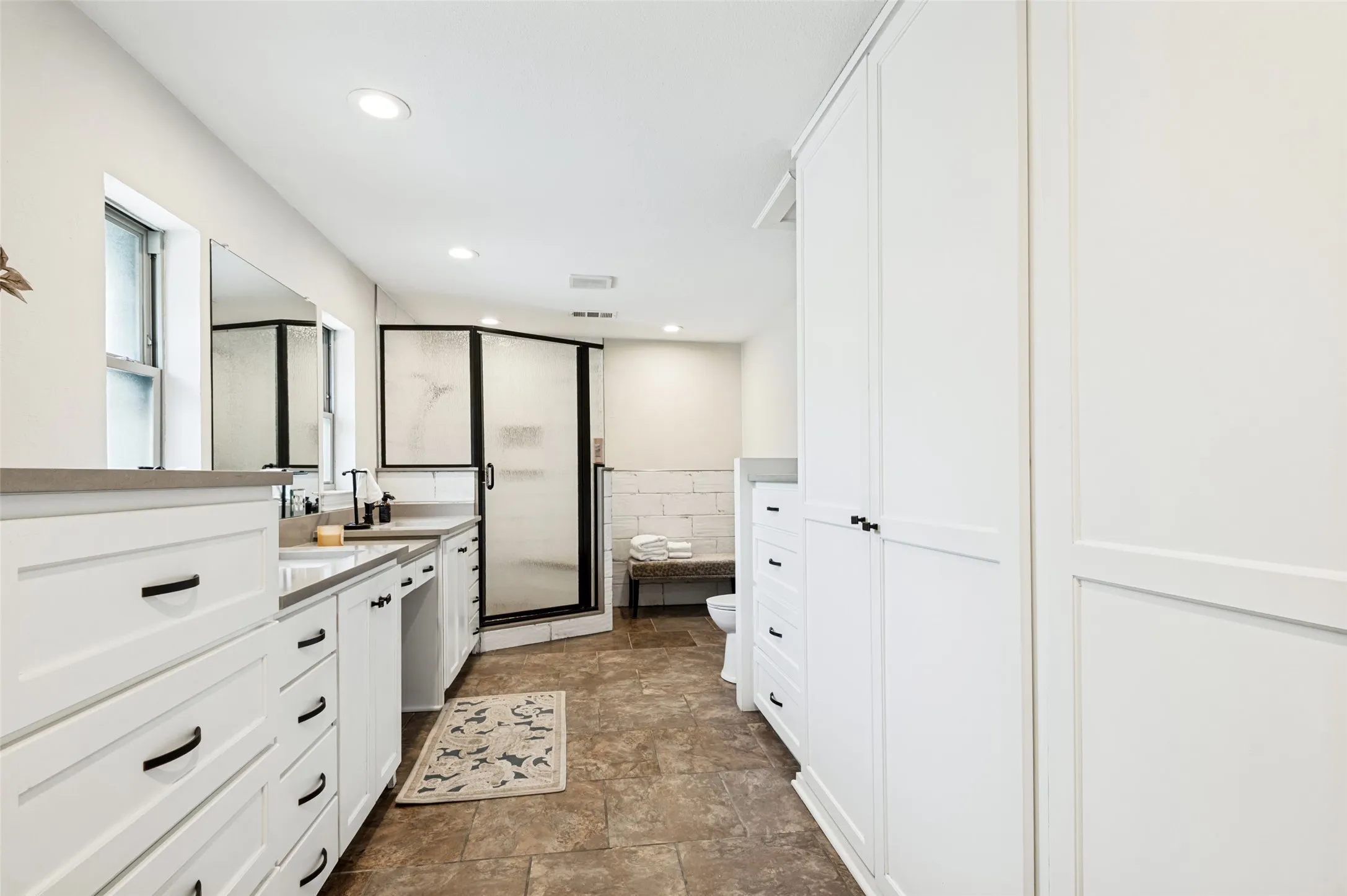 Dual vanity with undermount sinks, stone countertops, and black fixtures