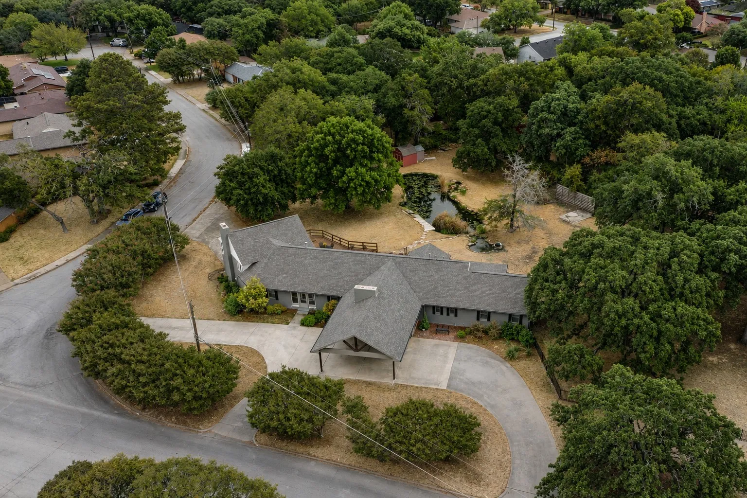 Expansive lot featuring mature trees, a driveway, and a pond