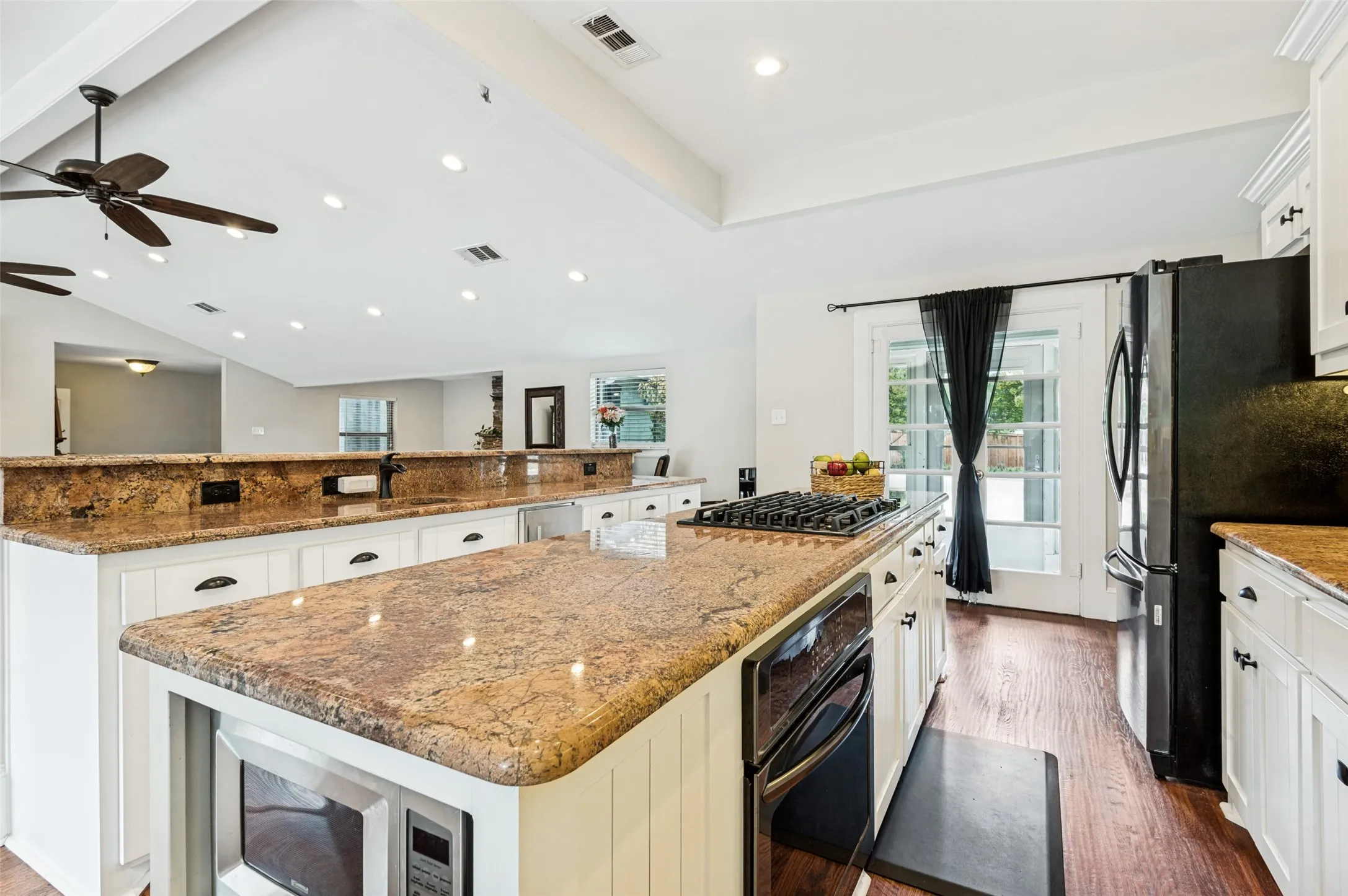 Kitchen featuring wood-finish flooring, white cabinetry, granite countertops, and built-in appliances