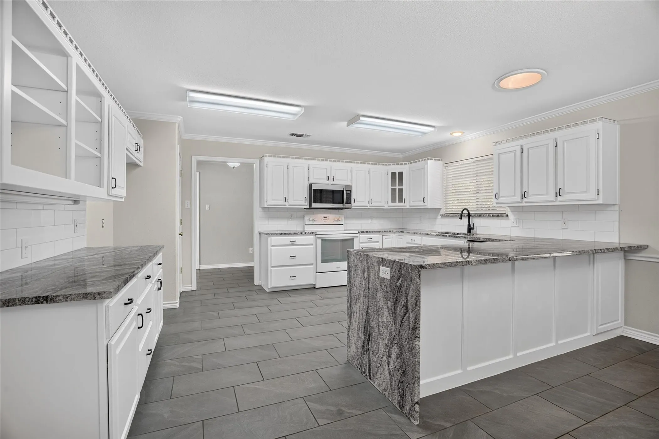 Kitchen featuring white cabinetry, stone countertops, a tile backsplash, stainless steel appliances, and tile flooring