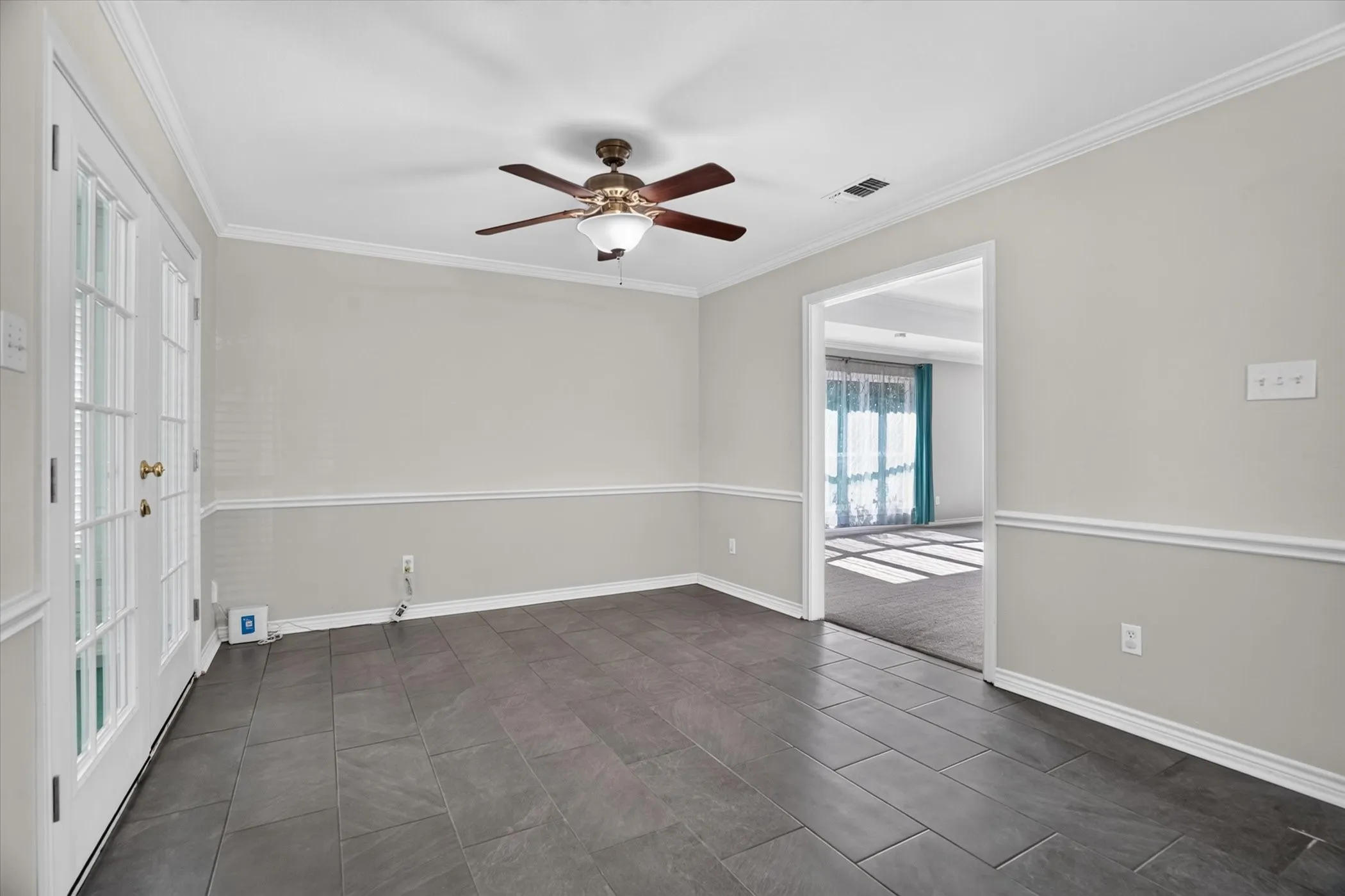 Room featuring tile flooring, white crown molding, and a ceiling fan with integrated lighting