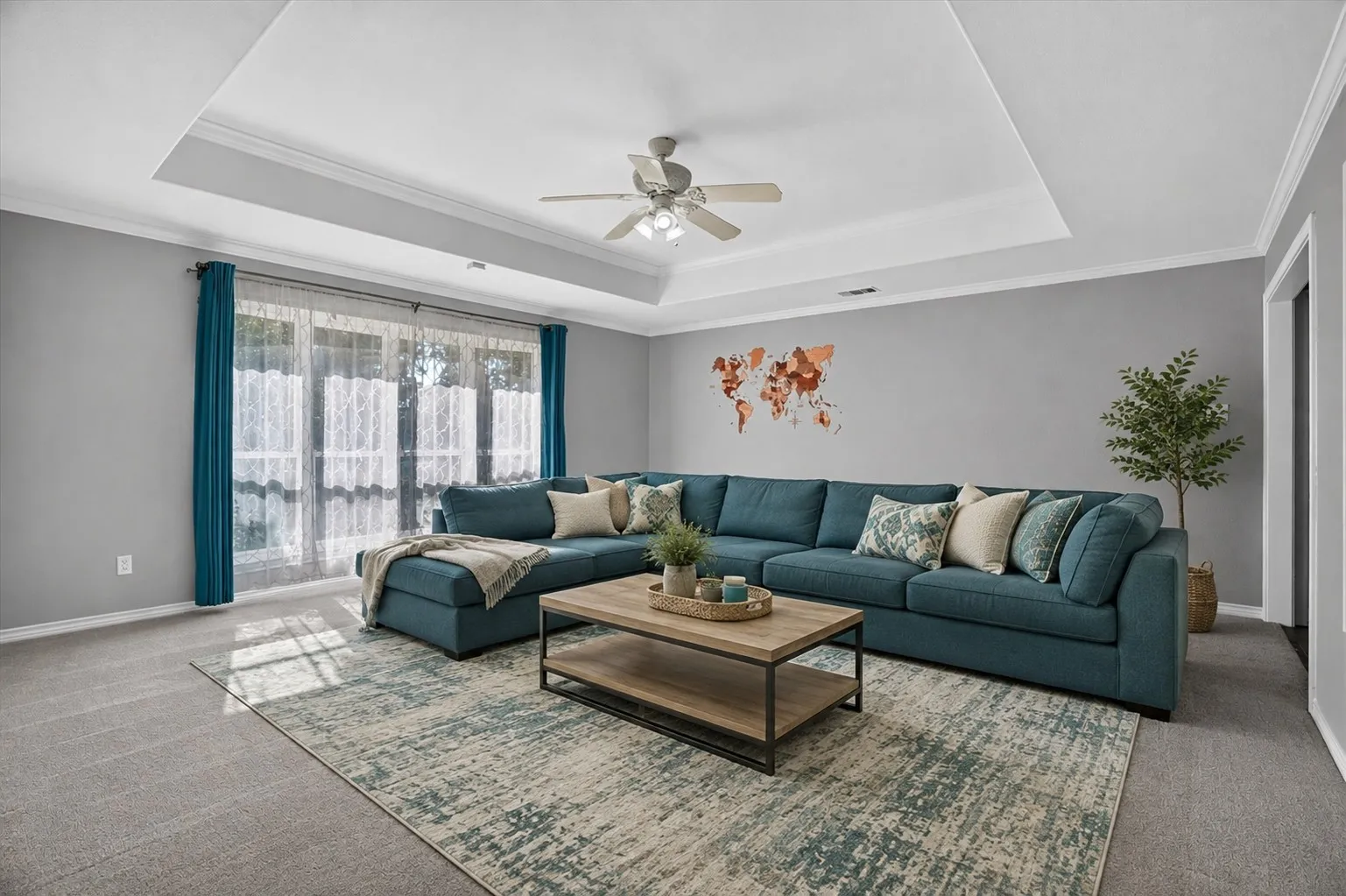 virtually staged
Tray ceiling with crown molding, ceiling fan, expansive window, neutral wall paint, and carpet flooring