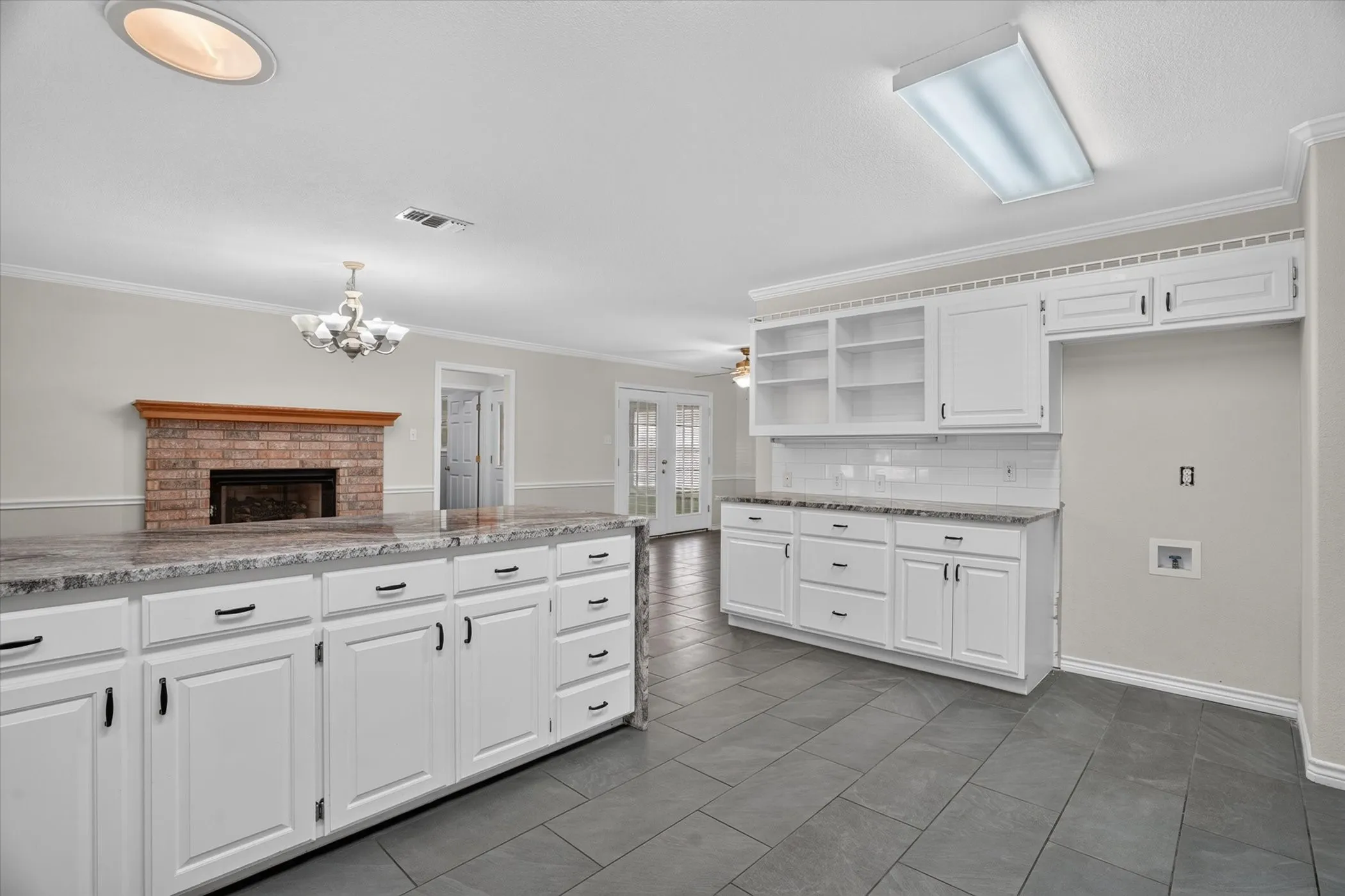 White cabinetry with dark hardware, stone countertops, and gray tile flooring