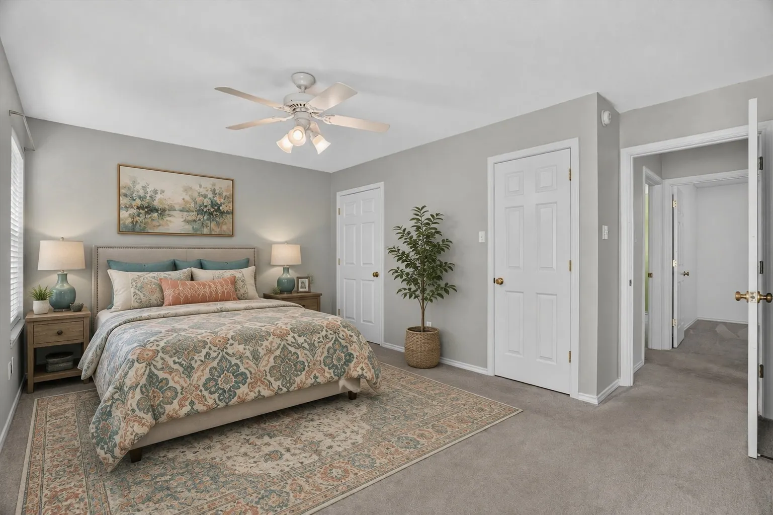 Virtually staged
Spacious primary bedroom with neutral gray walls, ceiling fan with integrated lighting, and wood-finish nightstands flanking the bed