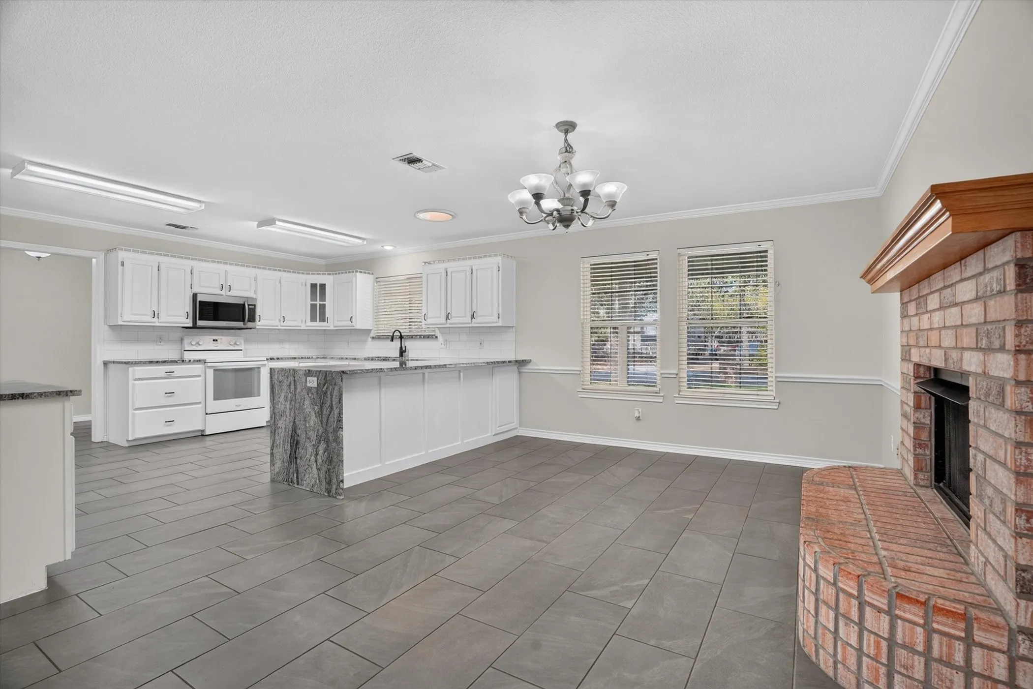 Kitchen featuring white cabinetry, stainless steel microwave, and an island with a contrasting stone countertop