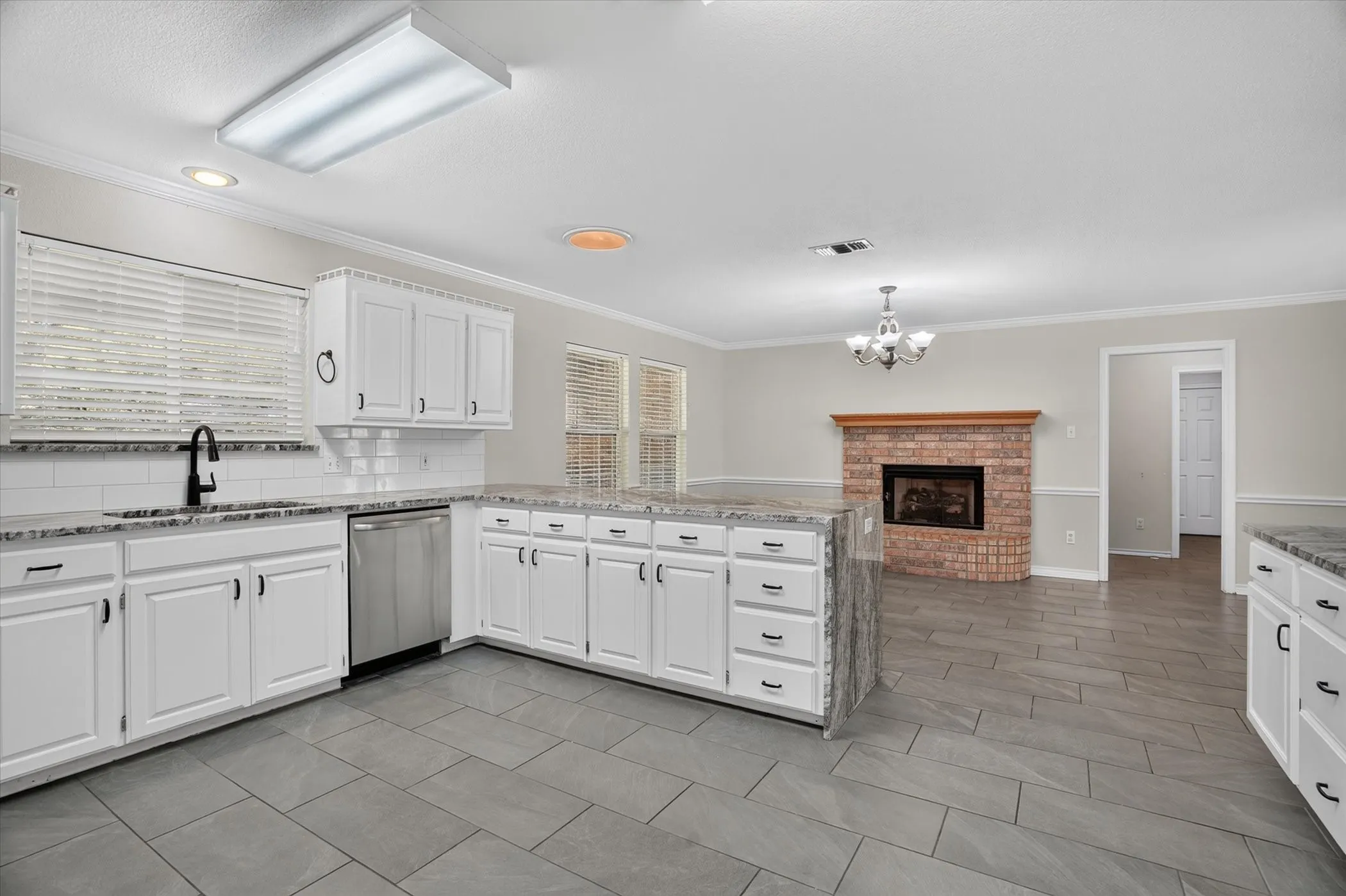 Bright kitchen featuring white cabinetry, granite countertops, subway tile backsplash, and stainless steel appliances