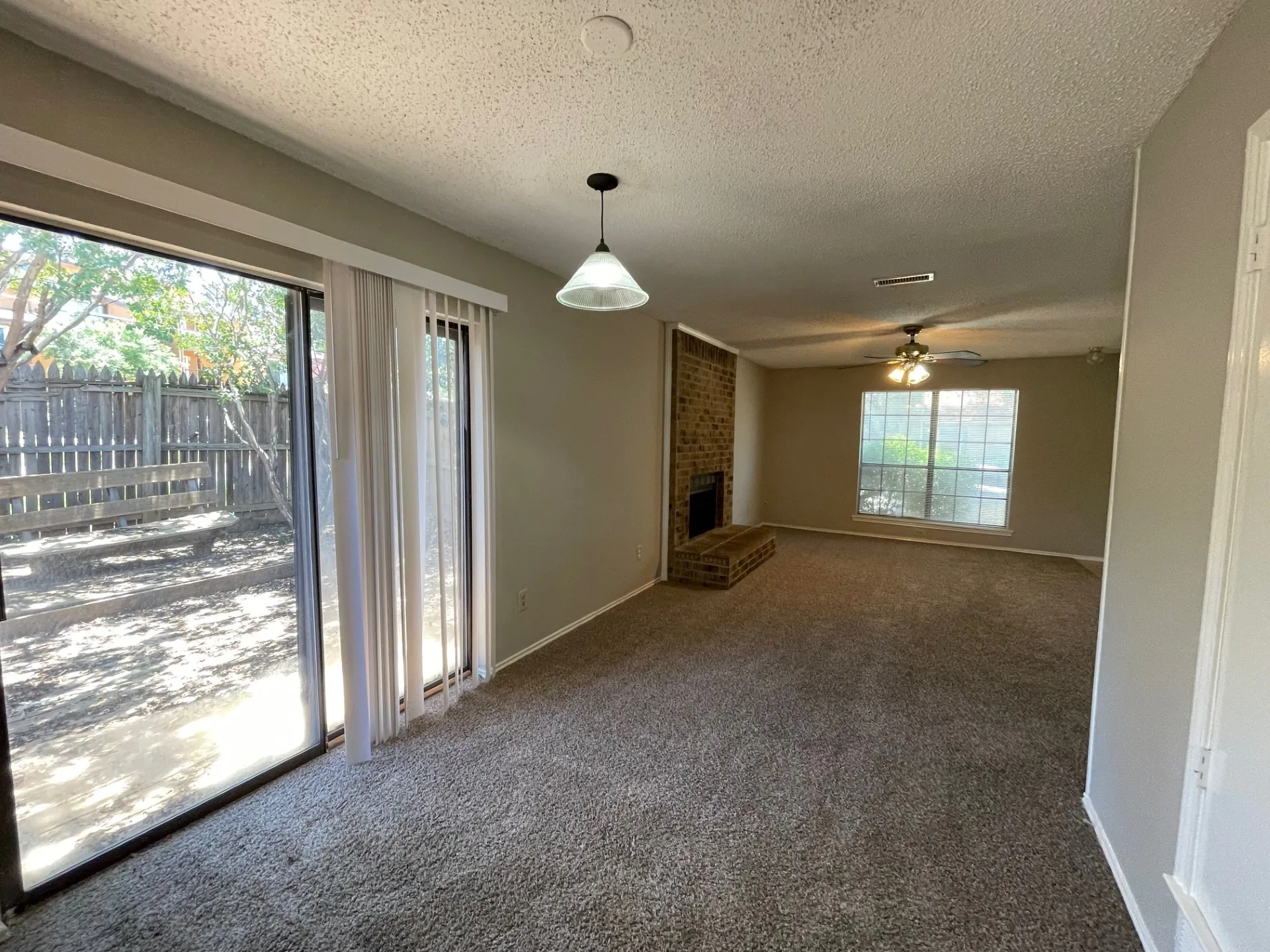 Unfurnished living room with carpet, a textured ceiling, a fireplace, and ceiling fan
