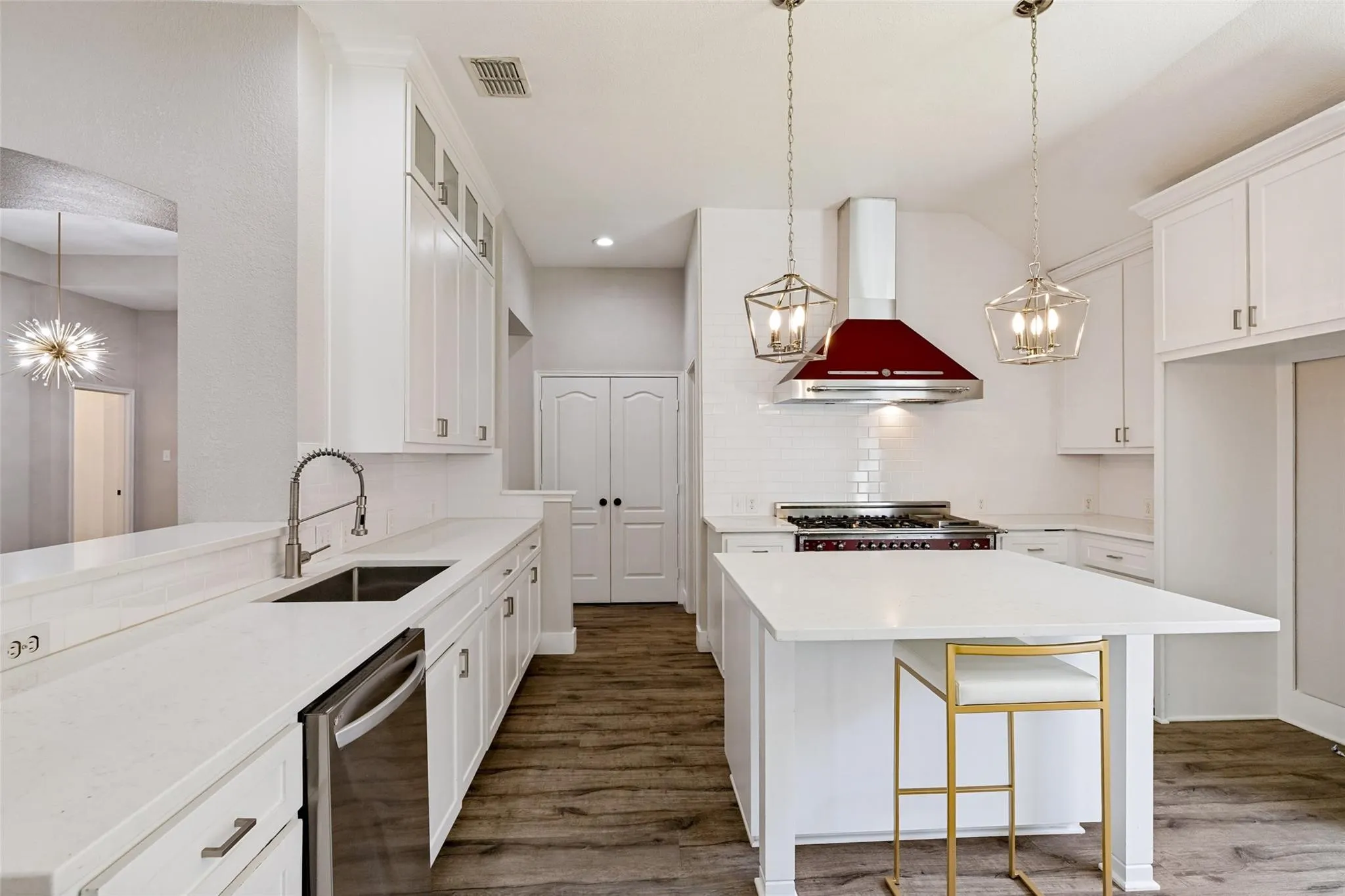 Gourmet kitchen featuring white cabinetry, a large center island, stainless steel appliances, a red range hood, and wood-finish flooring