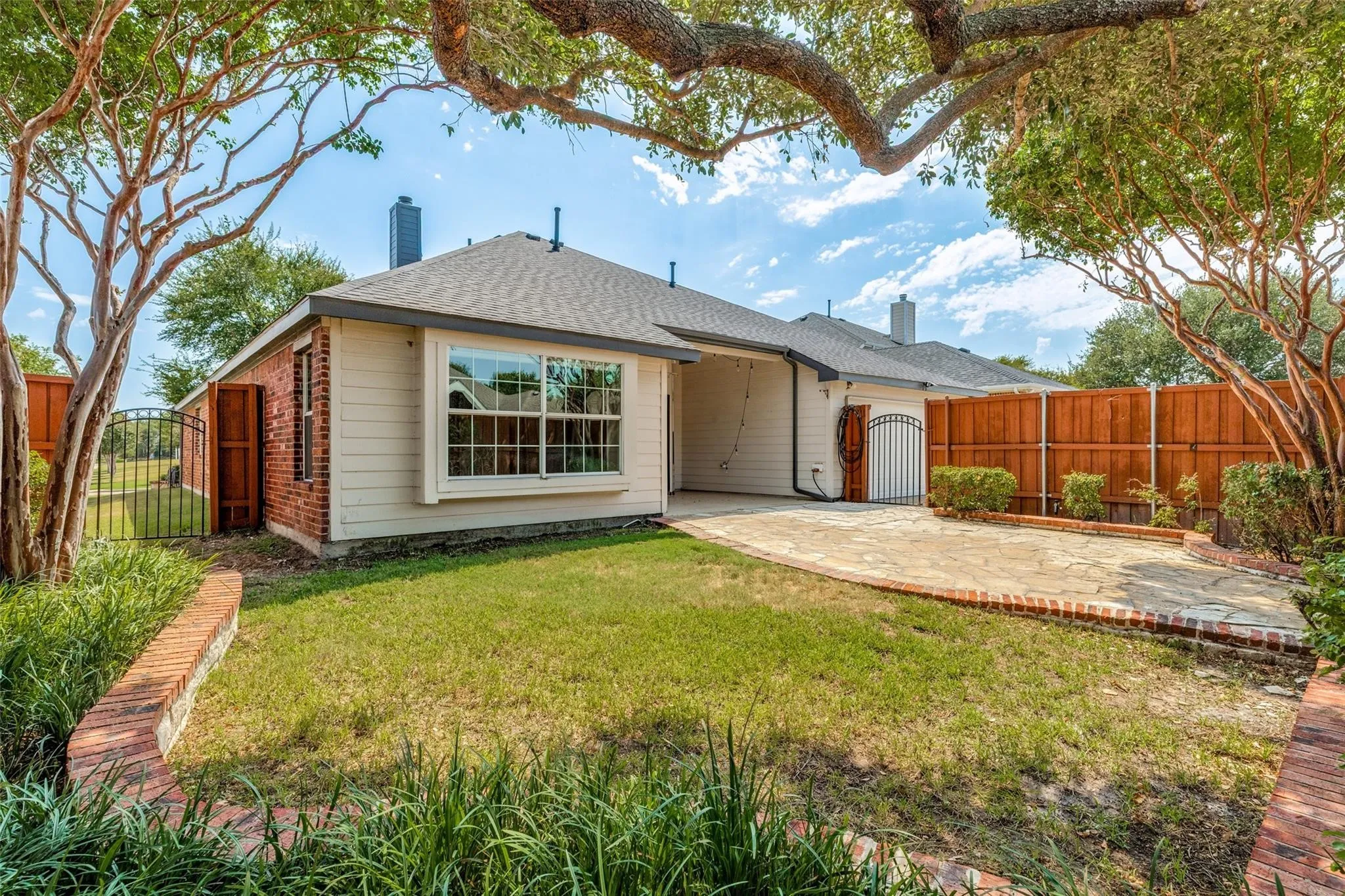 Expansive backyard with a stone patio, mature trees, and privacy fencing