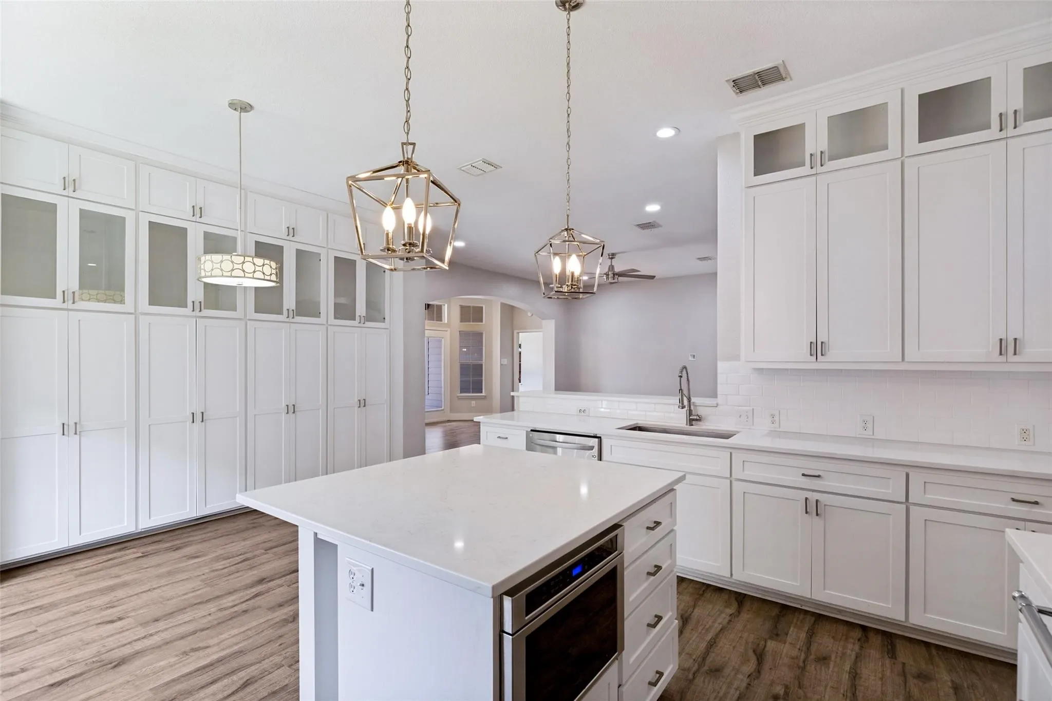 White cabinetry with glass-front uppers, wood-finish flooring, undermount sink, and recessed lighting