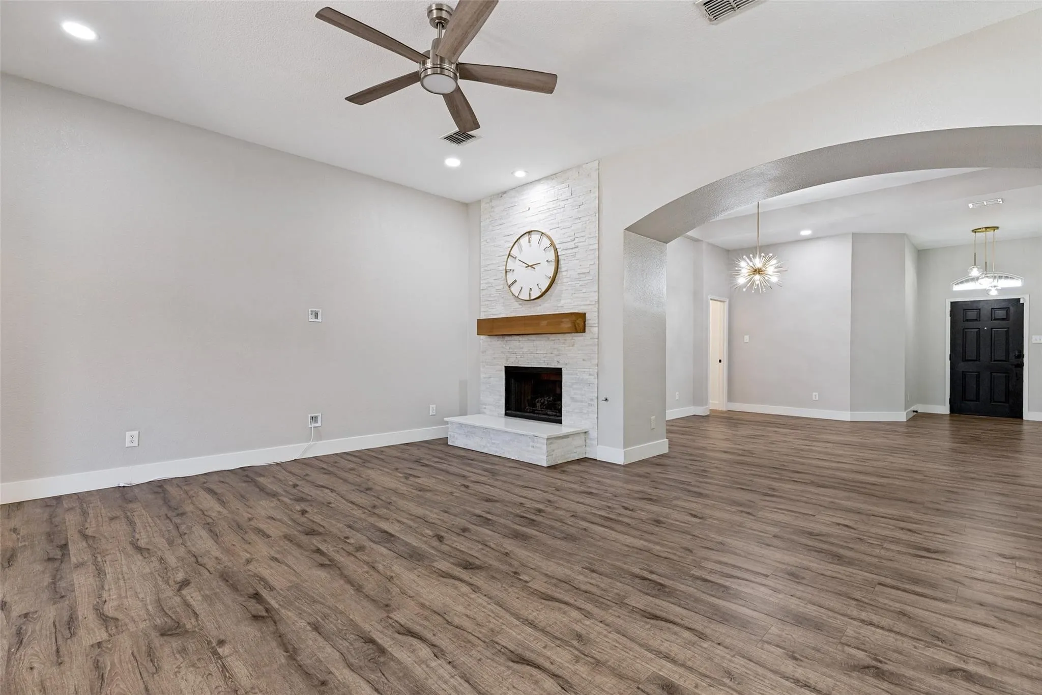 Wood-finish flooring throughout, featuring a white brick fireplace with a wood mantel