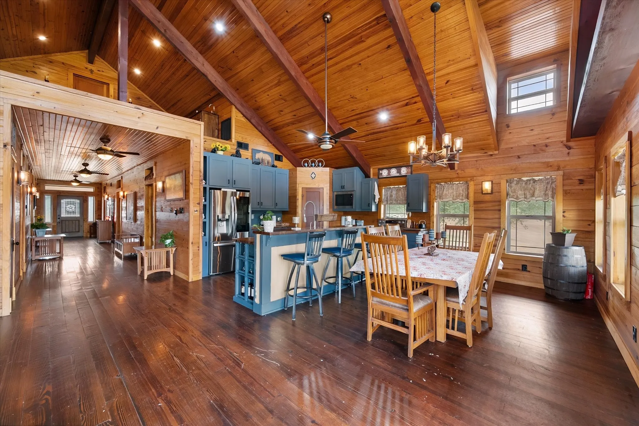 Vaulted wood-paneled ceilings with exposed beams, wood-finish flooring, a kitchen island with seating, built-in cabinetry, and integrated appliances
