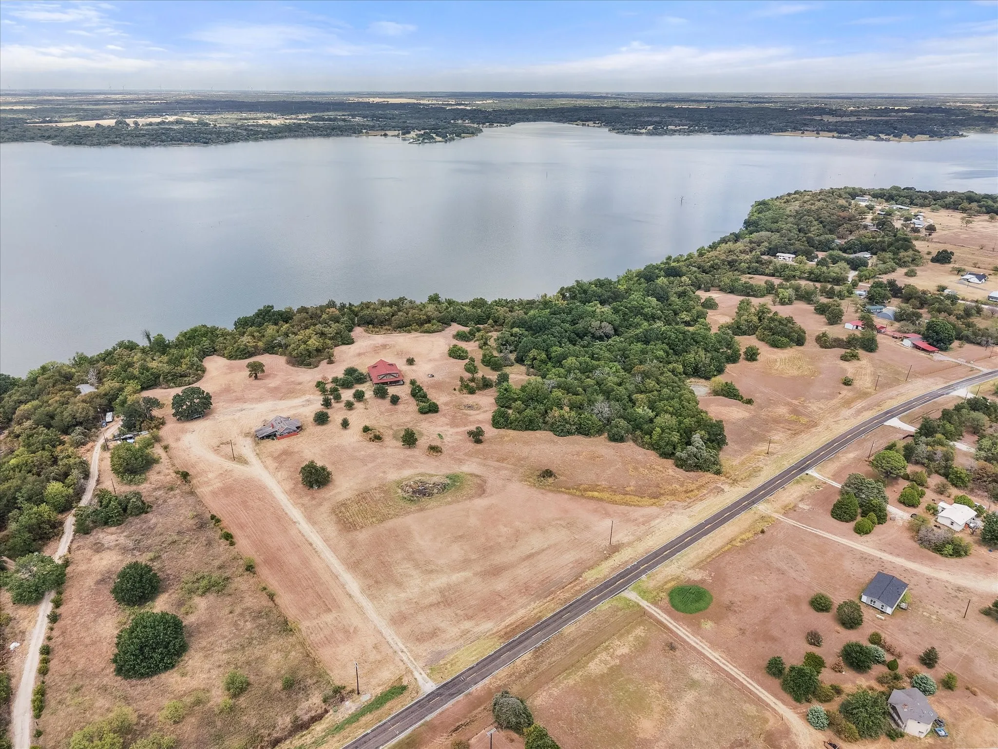 Expansive waterfront property featuring a lake, natural terrain, and visible road access