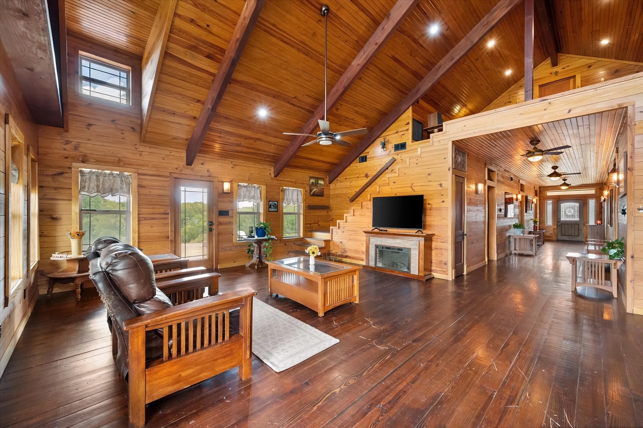 Spacious interior featuring wood-finish walls and ceilings, wood-finish flooring, a stone-surround fireplace, and an open loft area