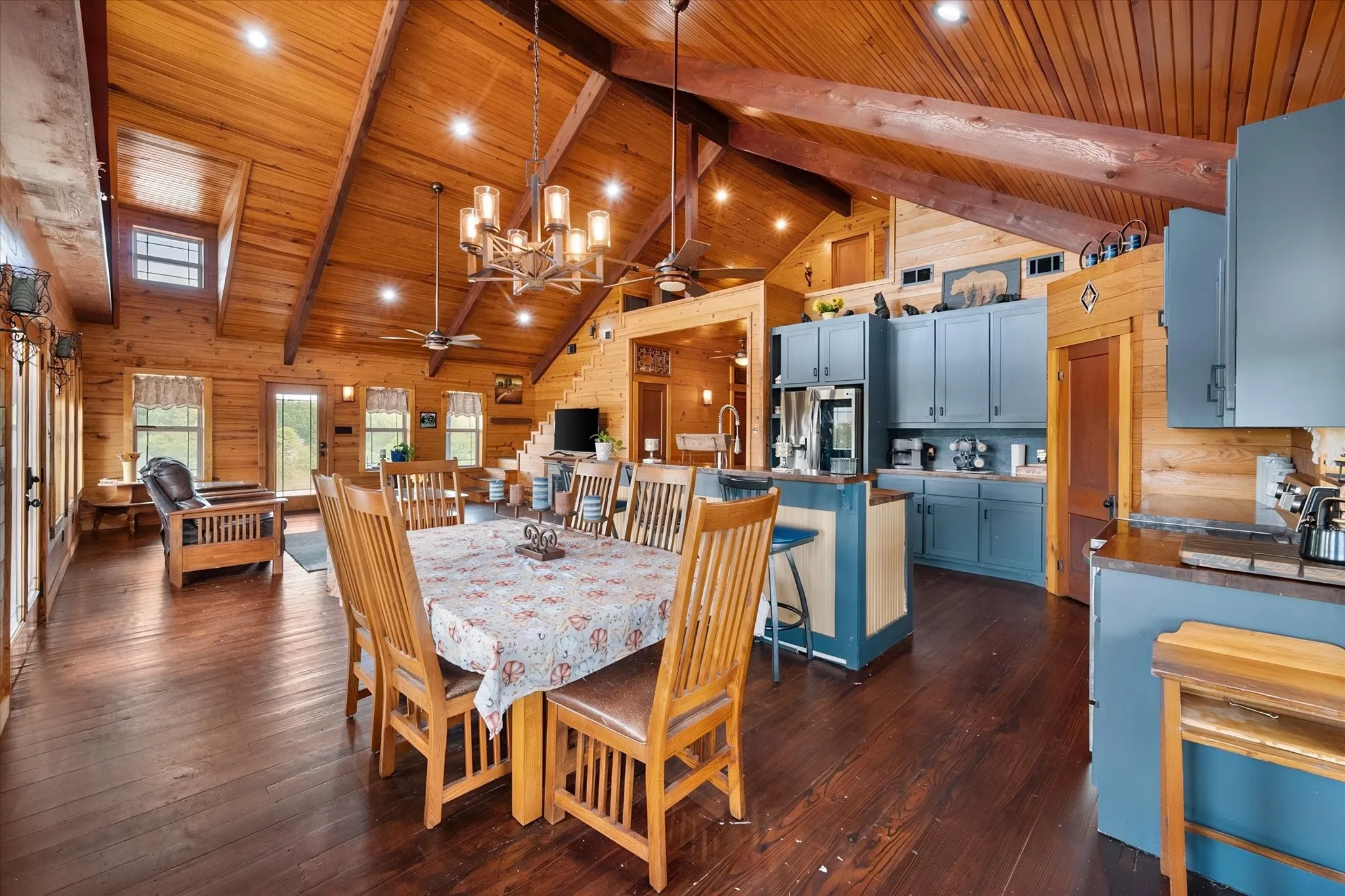 Open-concept living space featuring vaulted wood ceilings with exposed beams, recessed lighting, and skylights
