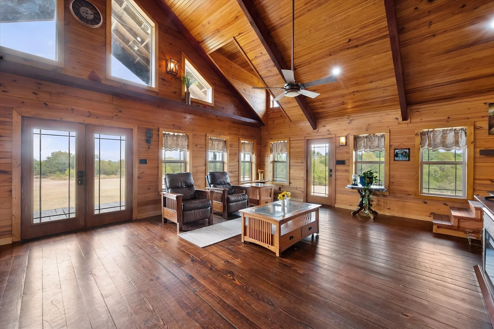 Spacious open-concept great room featuring soaring vaulted wood ceilings, exposed beams, and skylights flooding the space with natural light