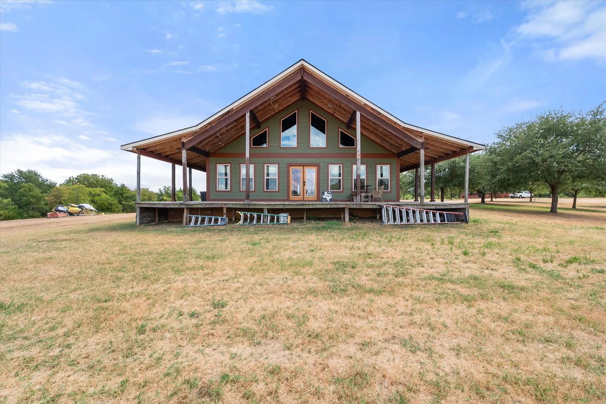 Expansive exterior featuring a wide covered porch, exposed wood beams, and a symmetrical facade with multiple windows