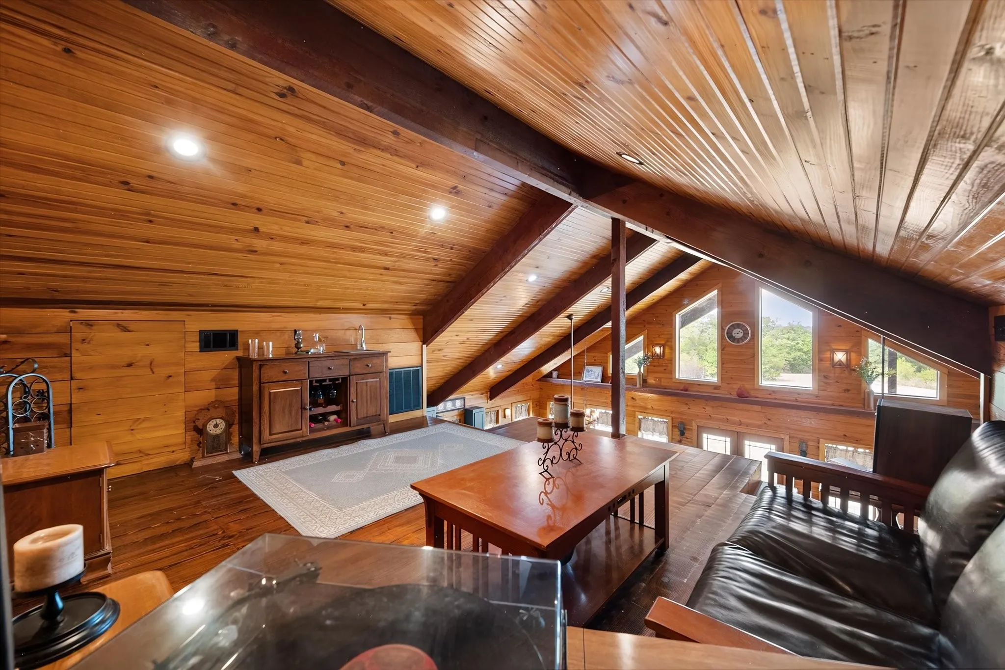 Wood-paneled ceilings with exposed beams, recessed lighting, and multiple windows