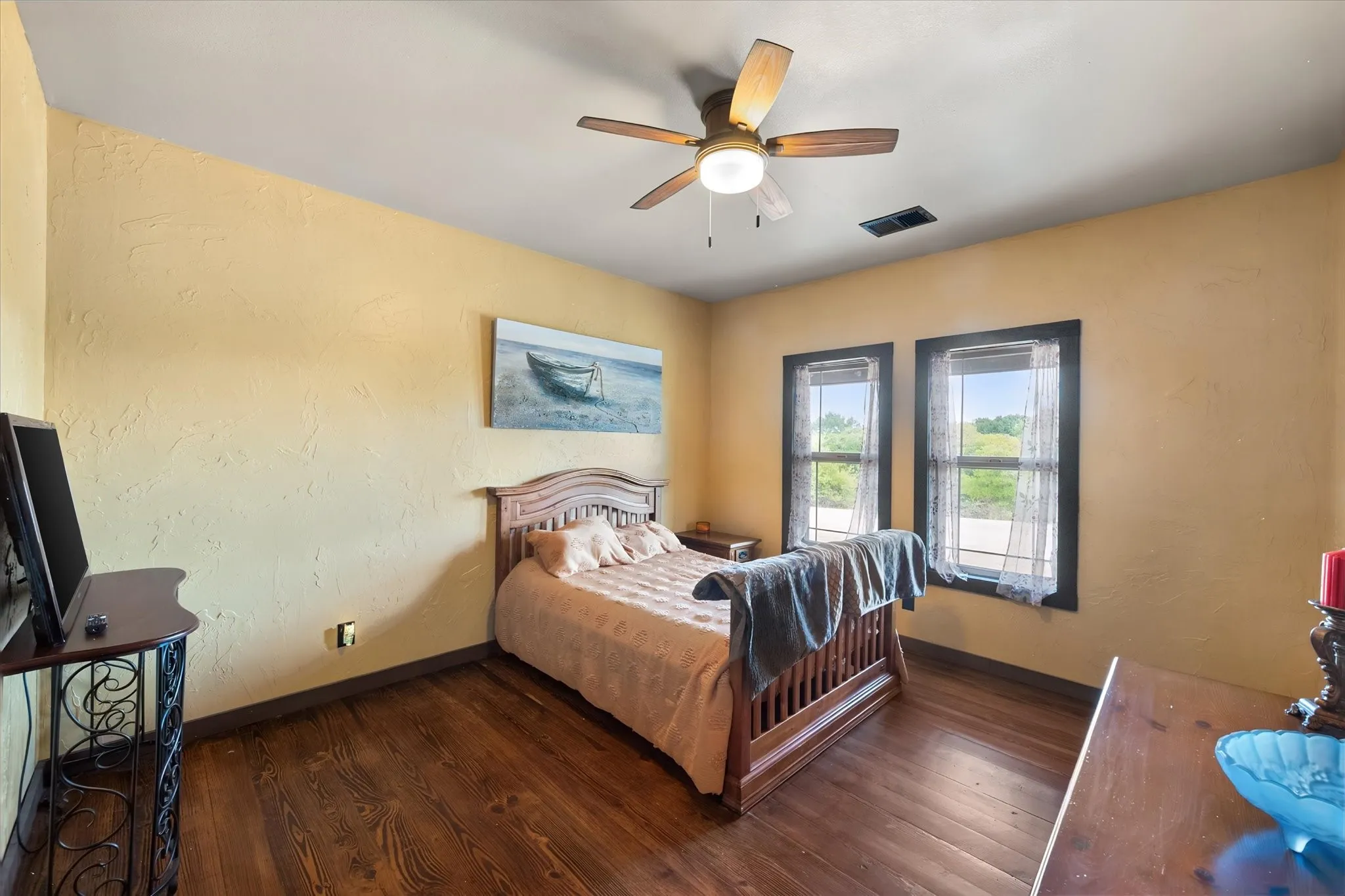 Wood-finish flooring, textured wall finish, and a ceiling fan with integrated lighting