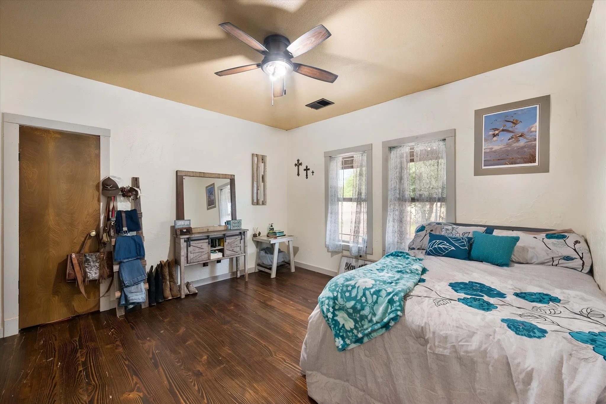 Wood-finish flooring, ceiling fan with integrated lighting, and multiple windows with trim