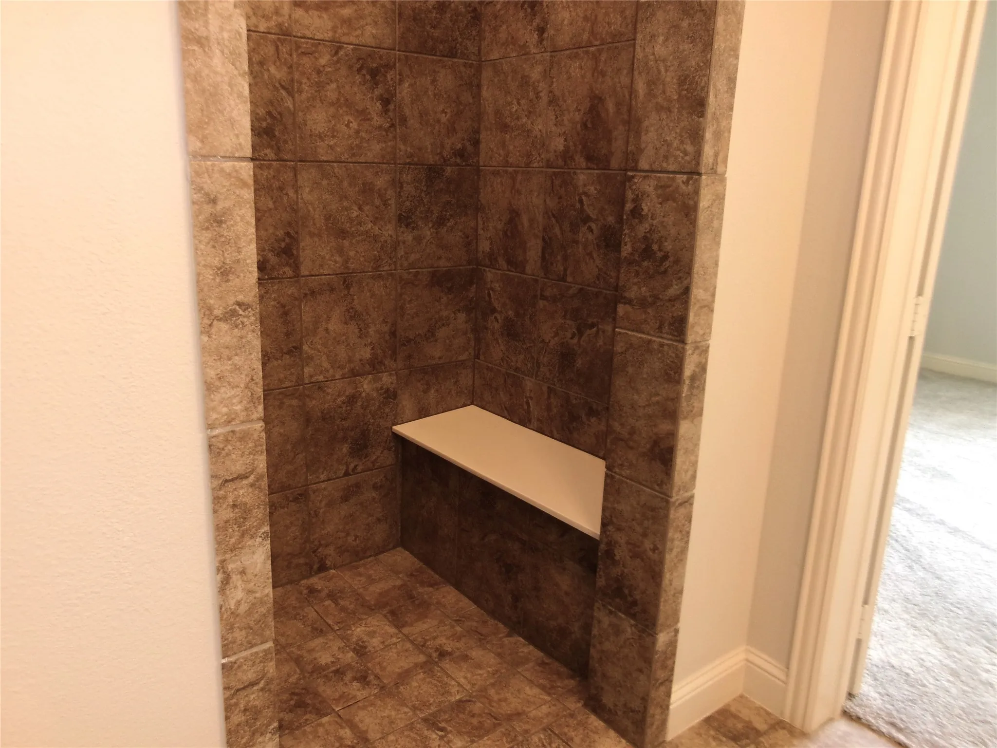 Primary bathroom shower showing doorless access for wheelchair and seating area