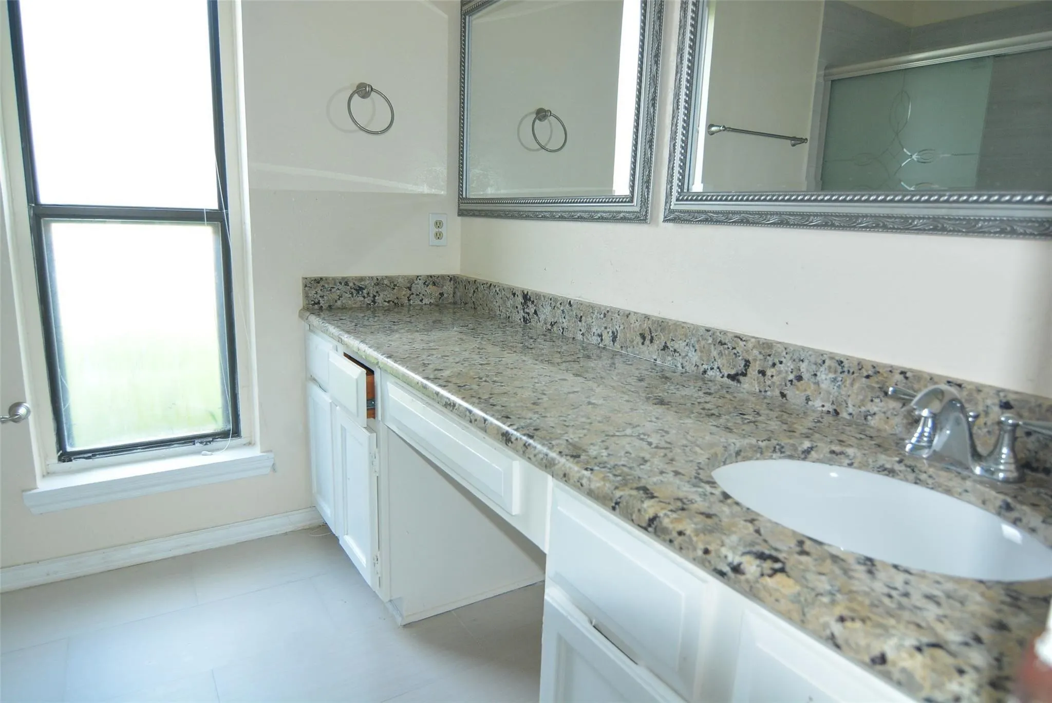 Double vanity with integrated sinks, speckled countertop, chrome fixtures, and white cabinetry