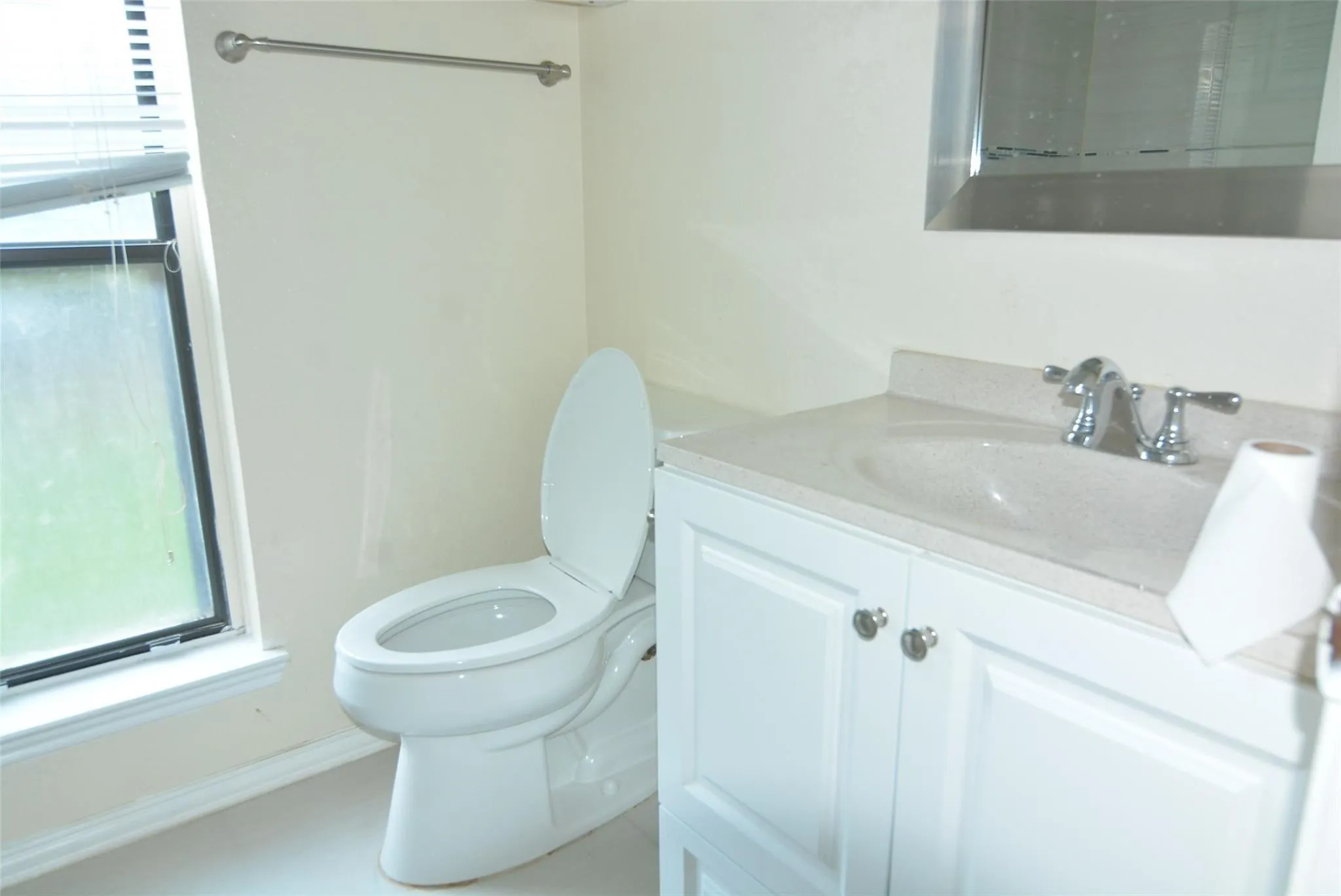 White vanity with panel-front cabinetry, integrated sink, and chrome faucet