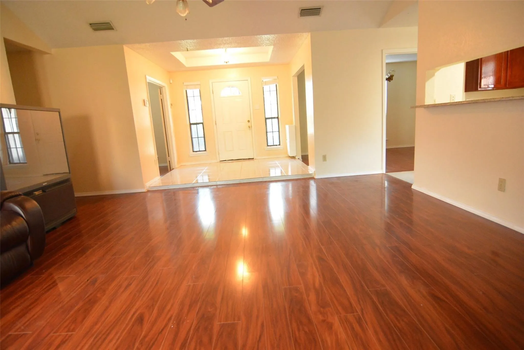 Wood-finish flooring throughout, with a tiled entry, recessed lighting, and a breakfast bar with upper cabinetry