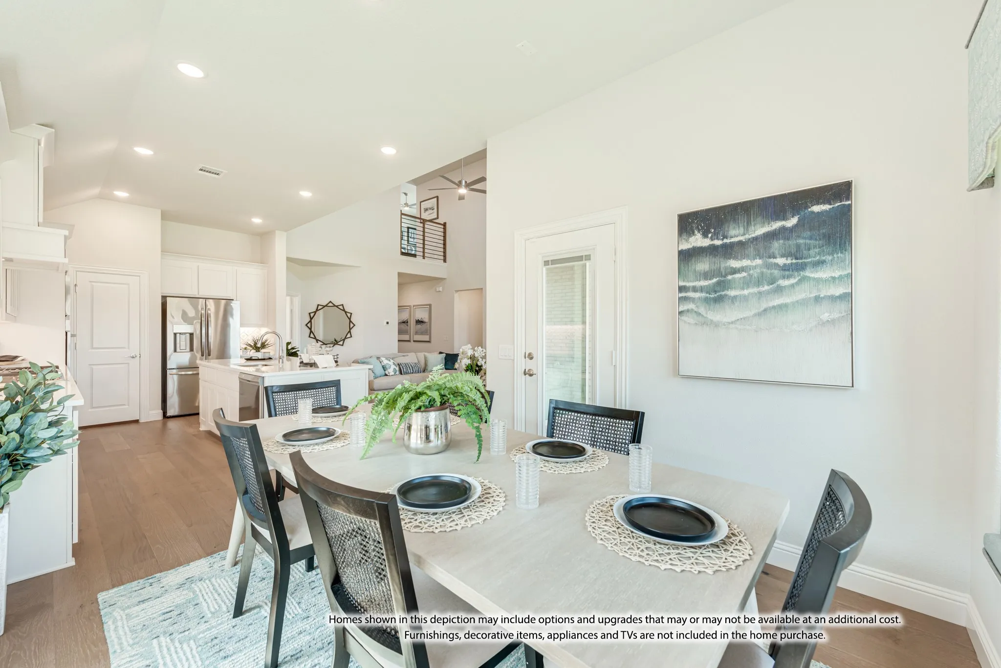 Wood-finish flooring throughout, white kitchen cabinetry, recessed lighting, double-height ceiling, and a stainless steel refrigerator
