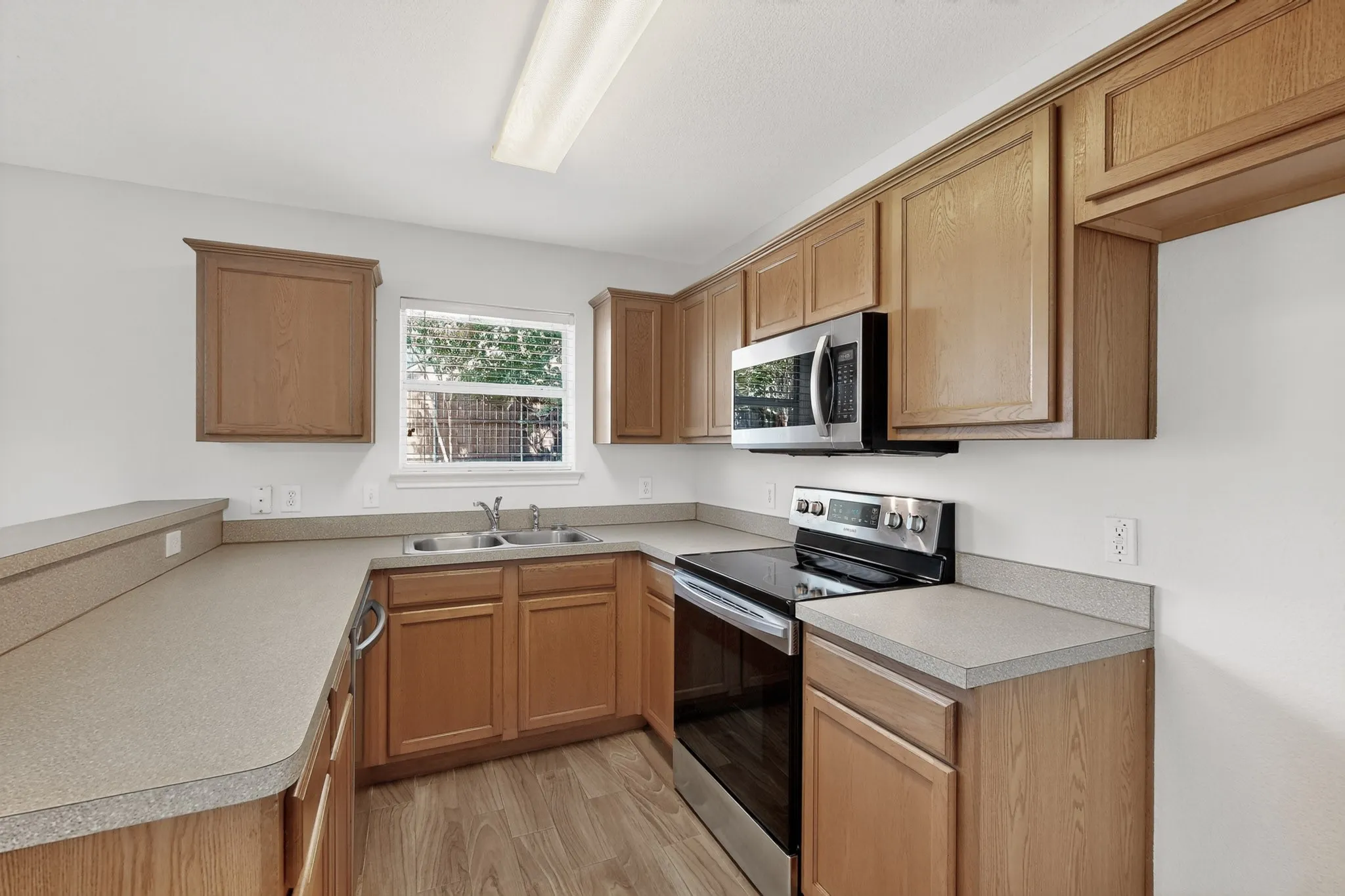 Kitchen featuring wood-finish cabinetry, light-toned countertops, and stainless steel appliances