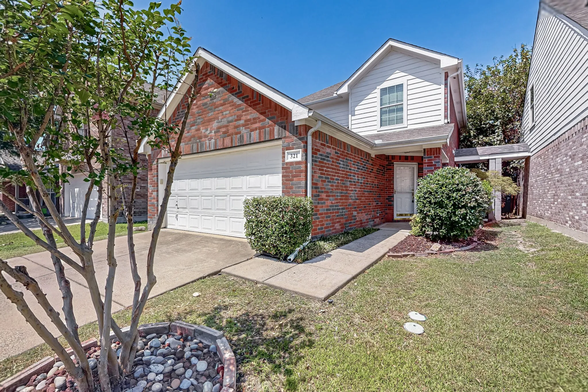 Brick and siding exterior with an attached garage, concrete driveway, and front walkway