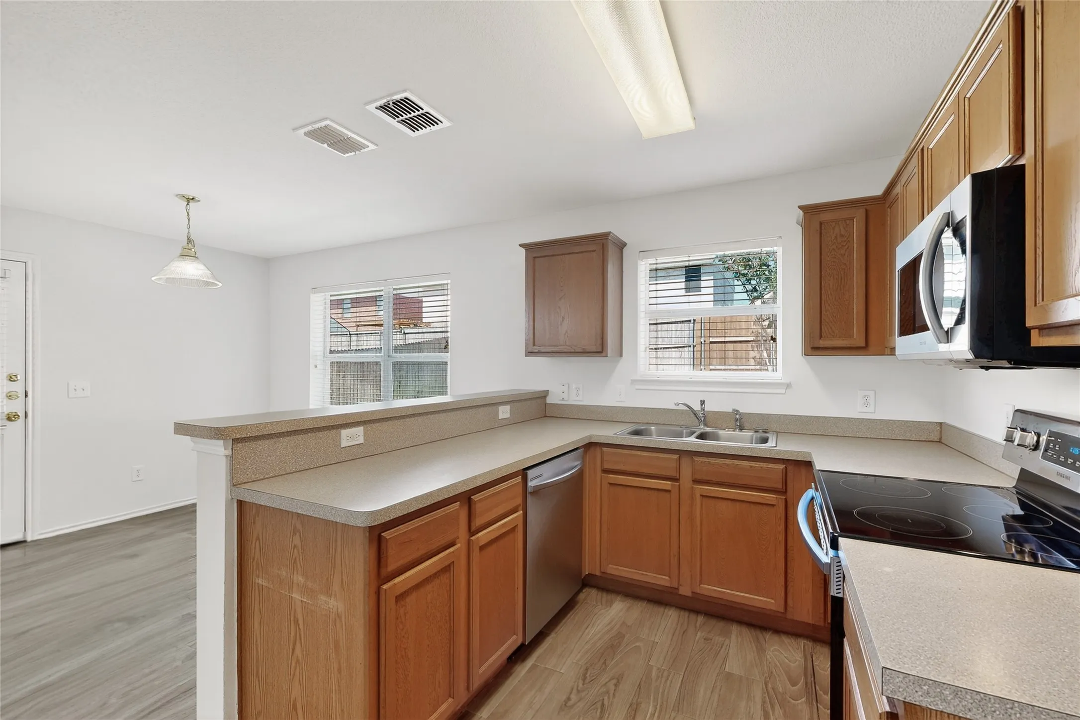 Kitchen featuring wood-finish flooring, wood cabinetry, a built-in microwave, and a black cooktop